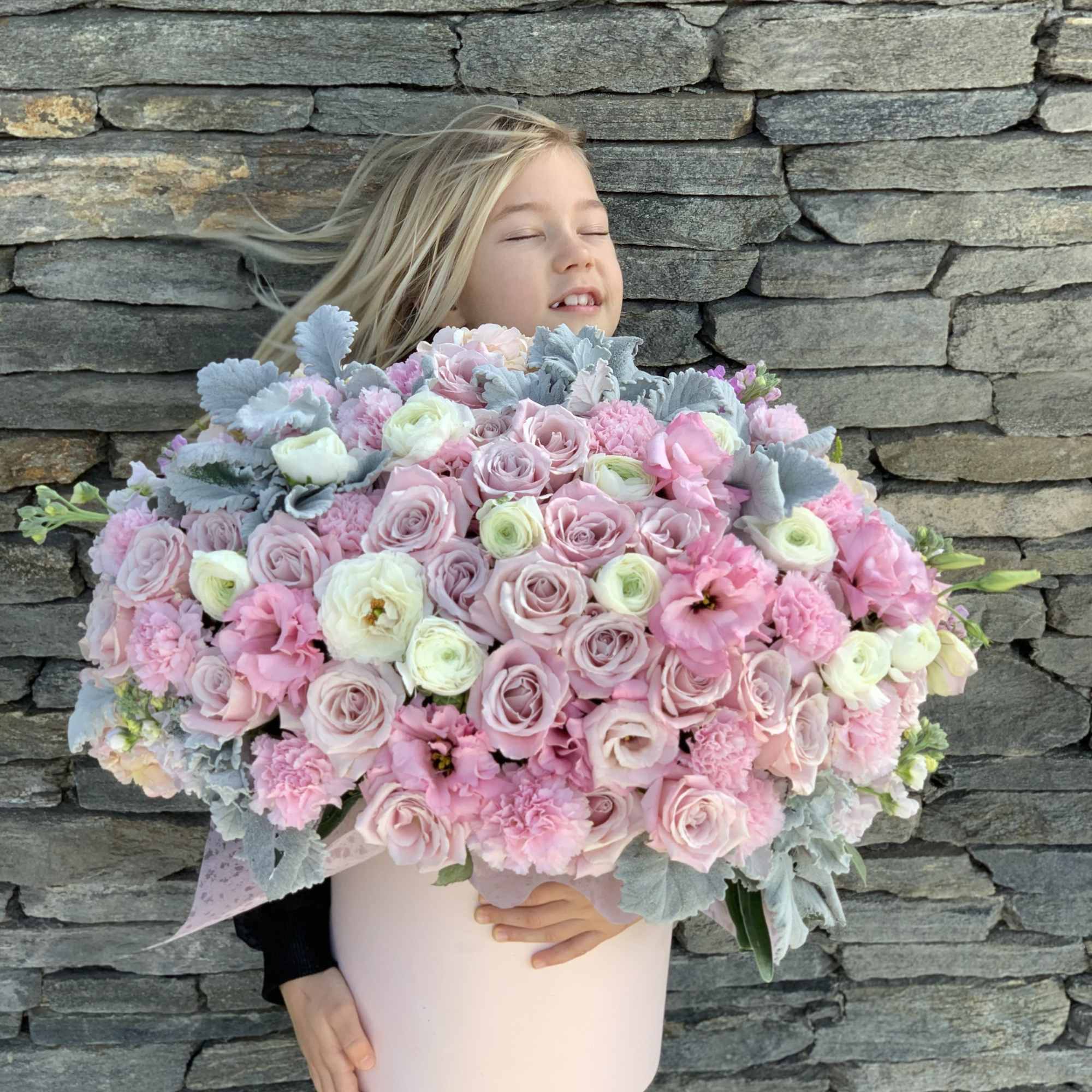 Girl holding a large pastel bouquet in a pink box