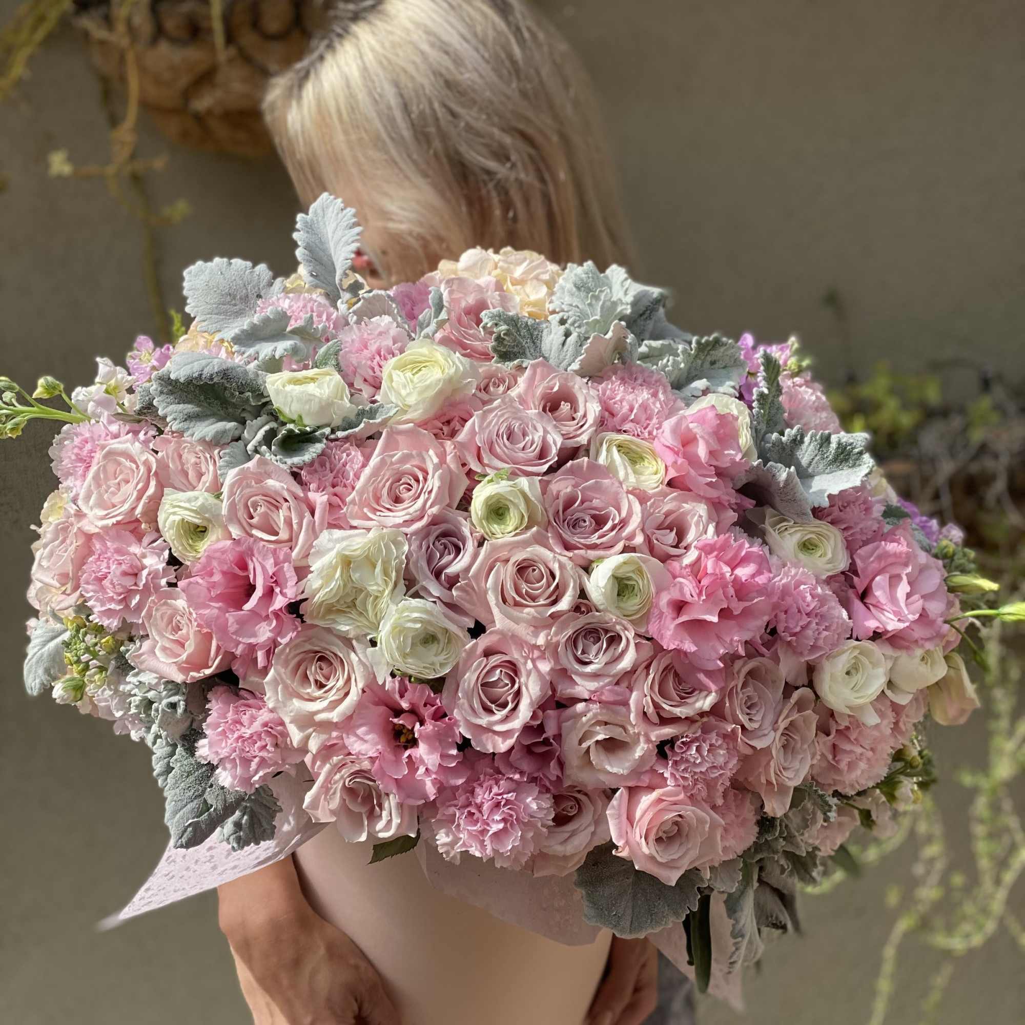 Large pink bouquet of roses and carnations held in a hatbox