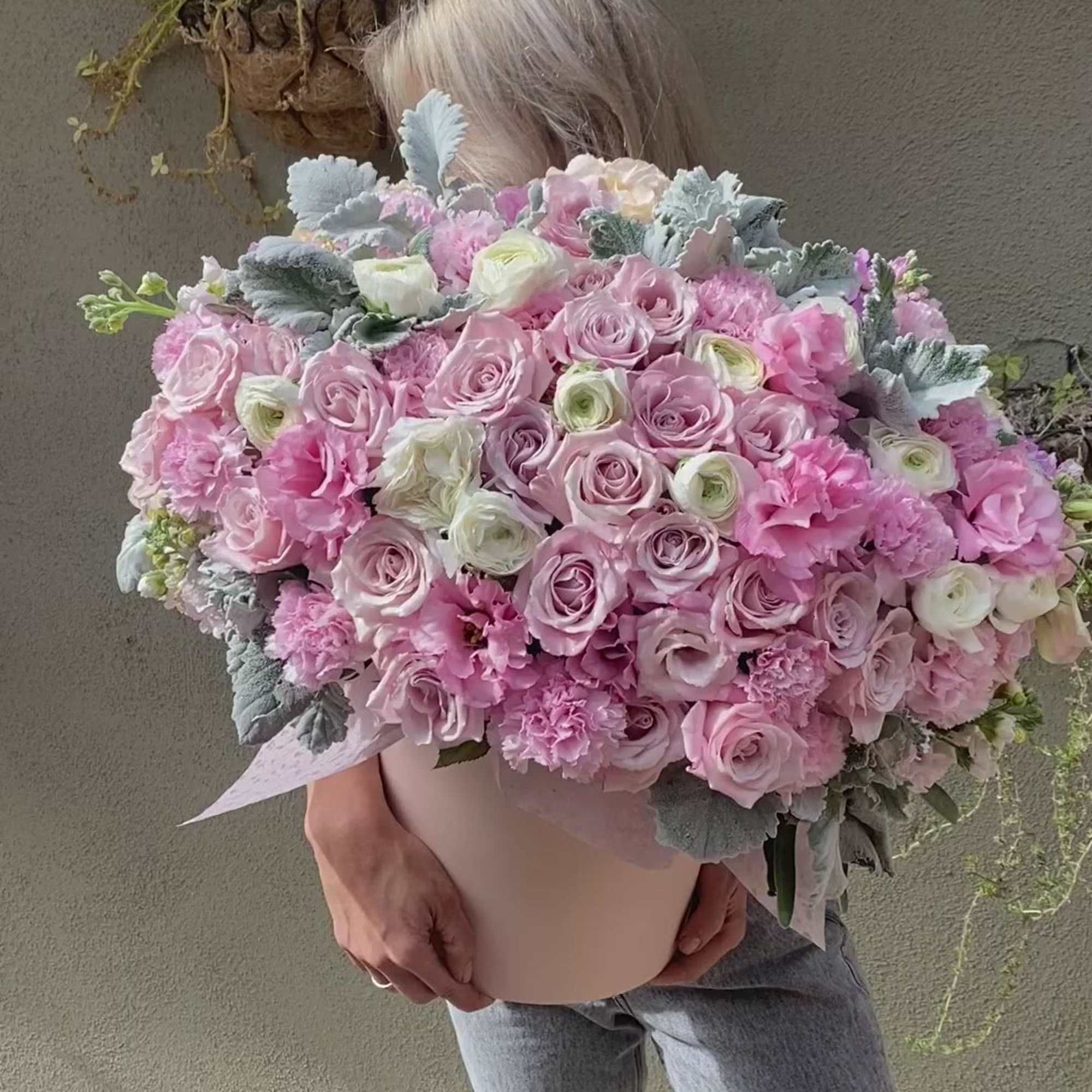 Large pink bouquet of roses and carnations held by a person