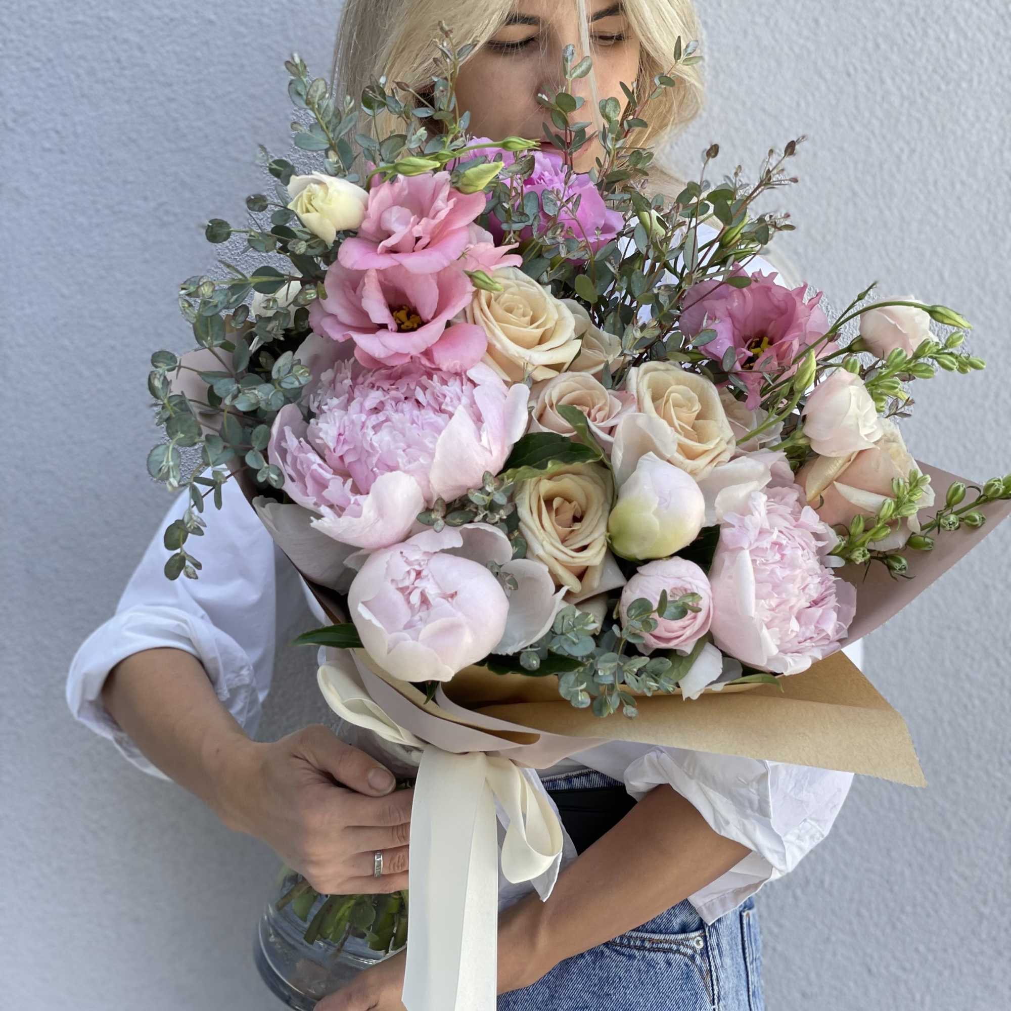 Large bouquet of pink and cream flowers wrapped in paper