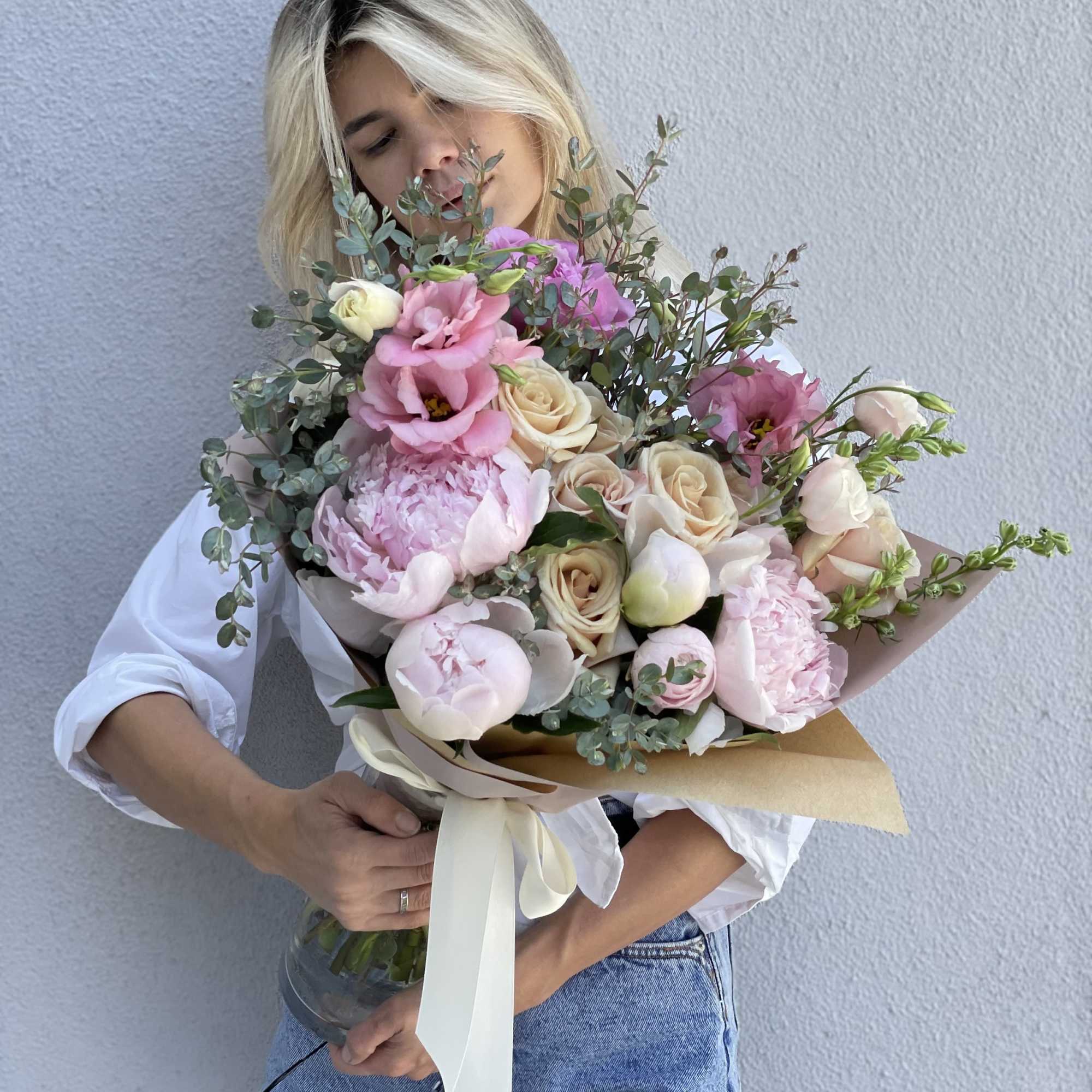Woman holding a large bouquet of pink and cream flowers