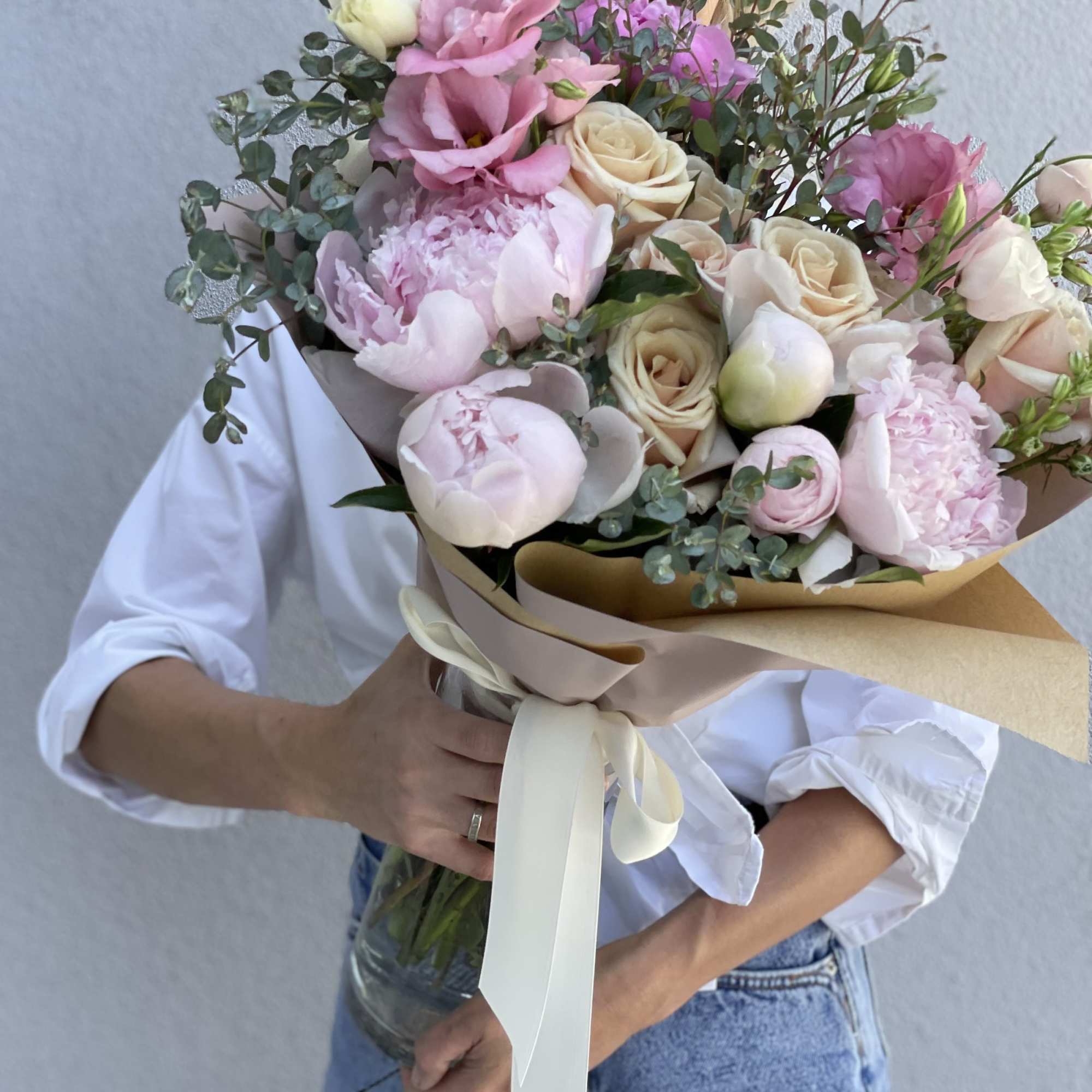 Bouquet of pink and cream roses with peonies in a glass vase