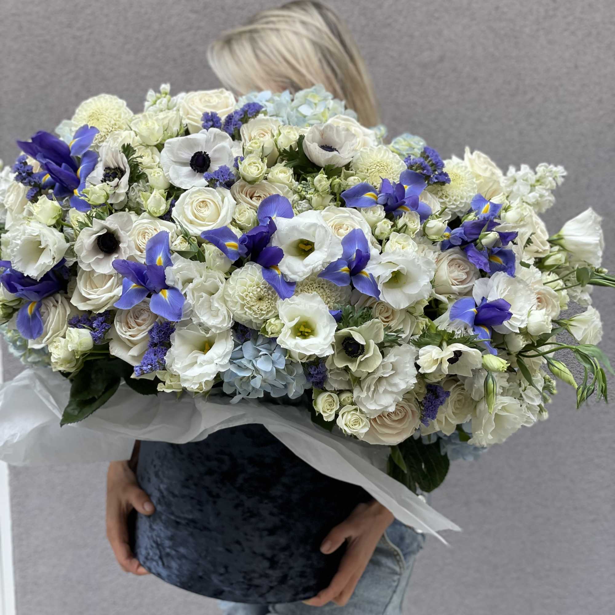 Large bouquet of white and blue flowers wrapped in paper