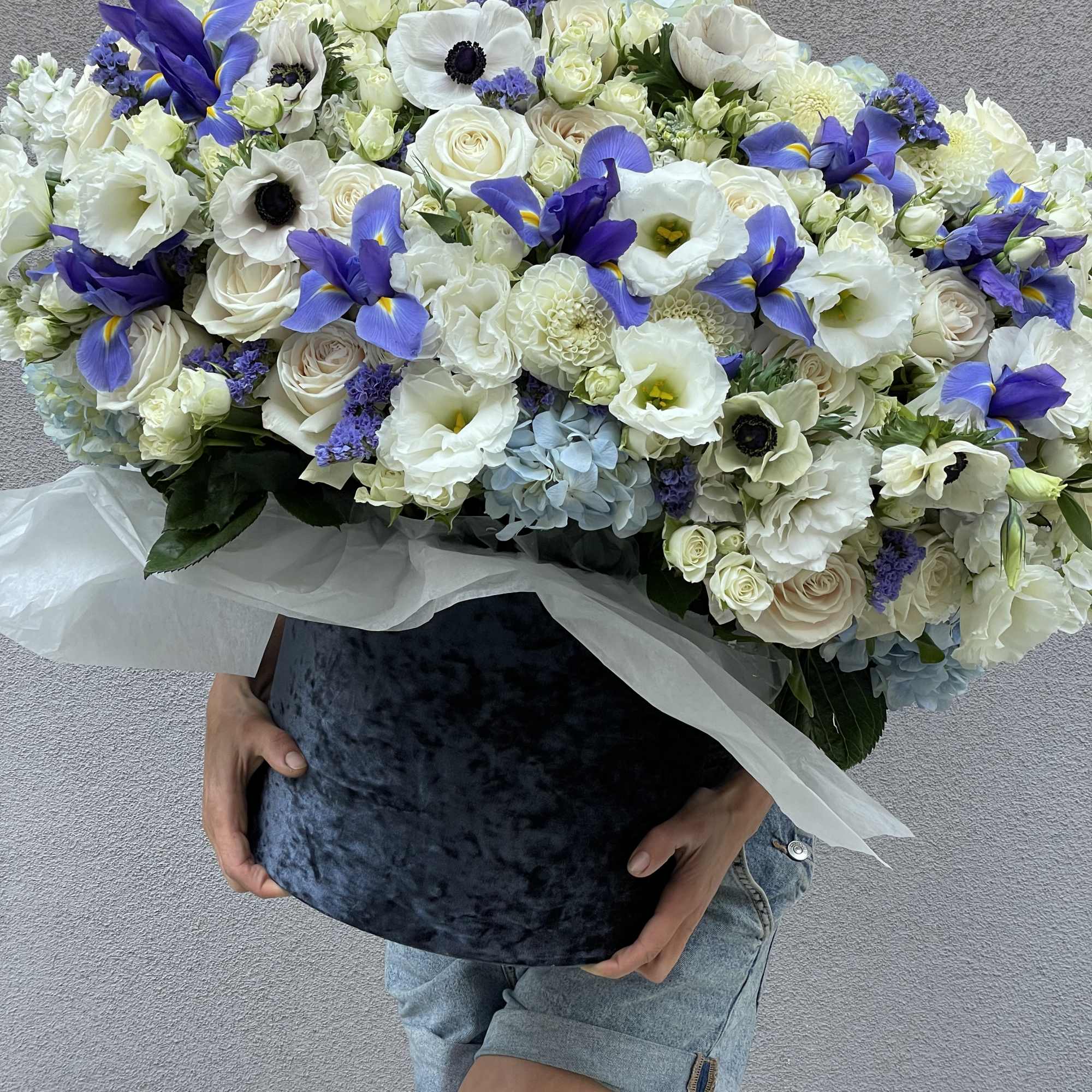 Large bouquet of white and blue flowers wrapped in white paper