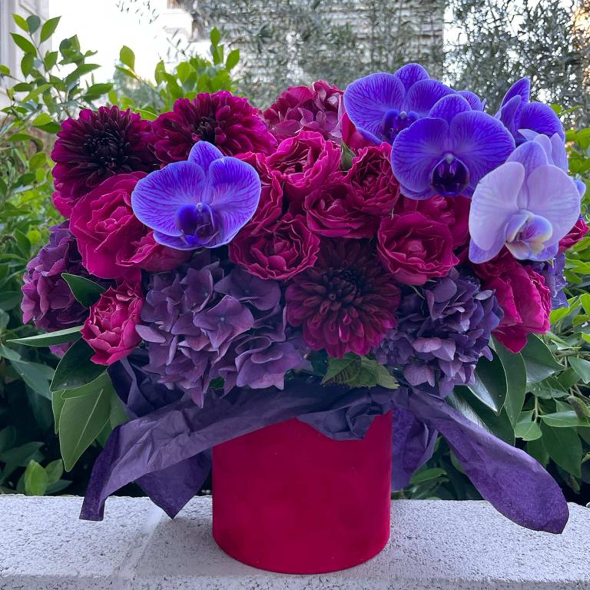 Bouquet of purple and magenta flowers in a red box