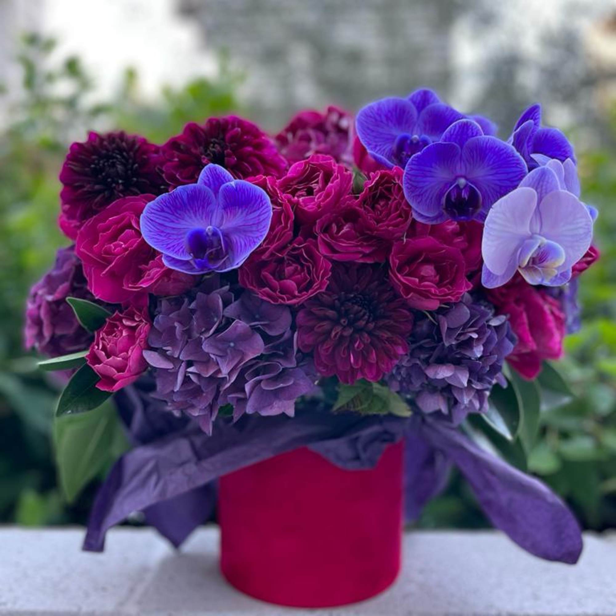 Purple and magenta bouquet with orchids in a red box