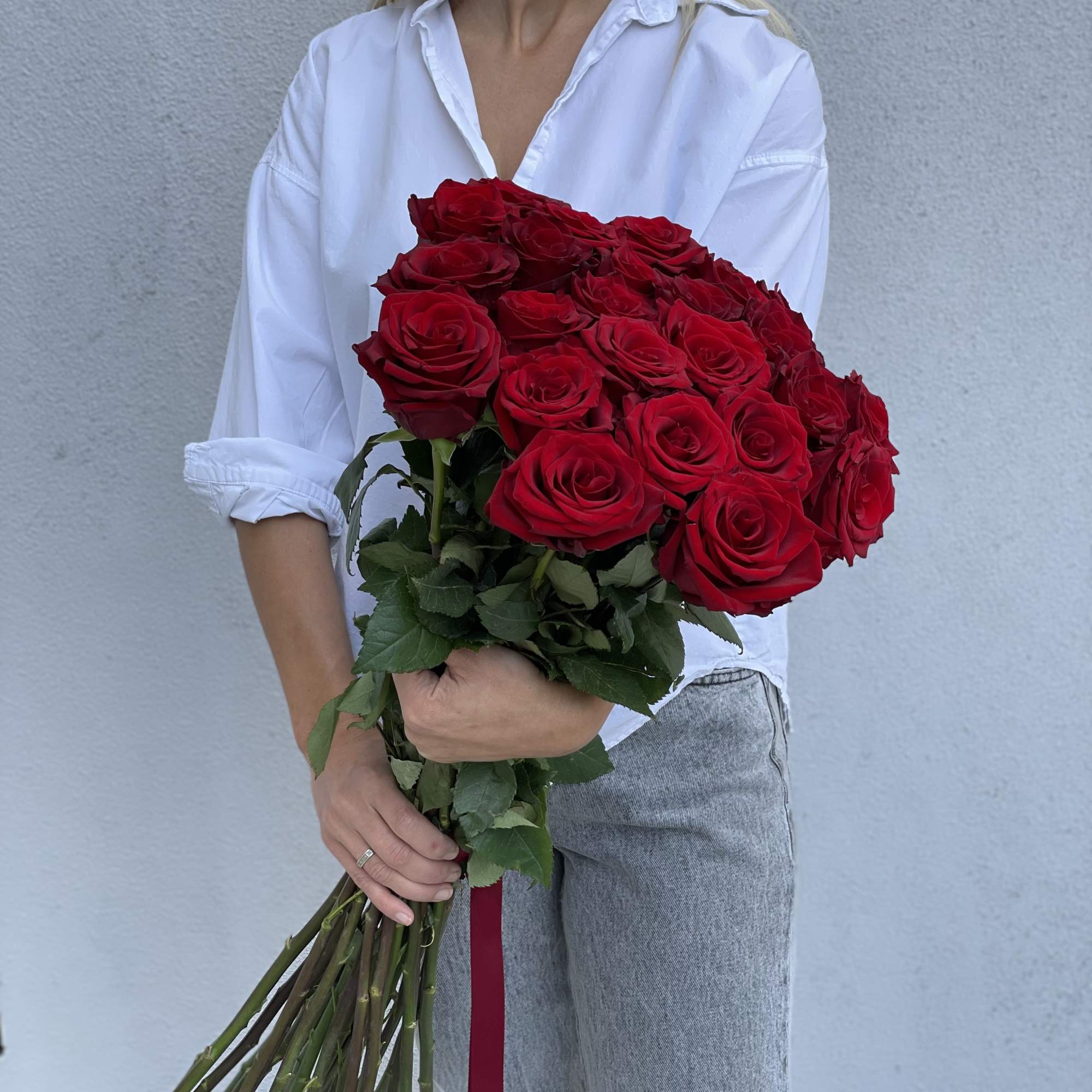 Bouquet of red roses held by a woman in a white shirt