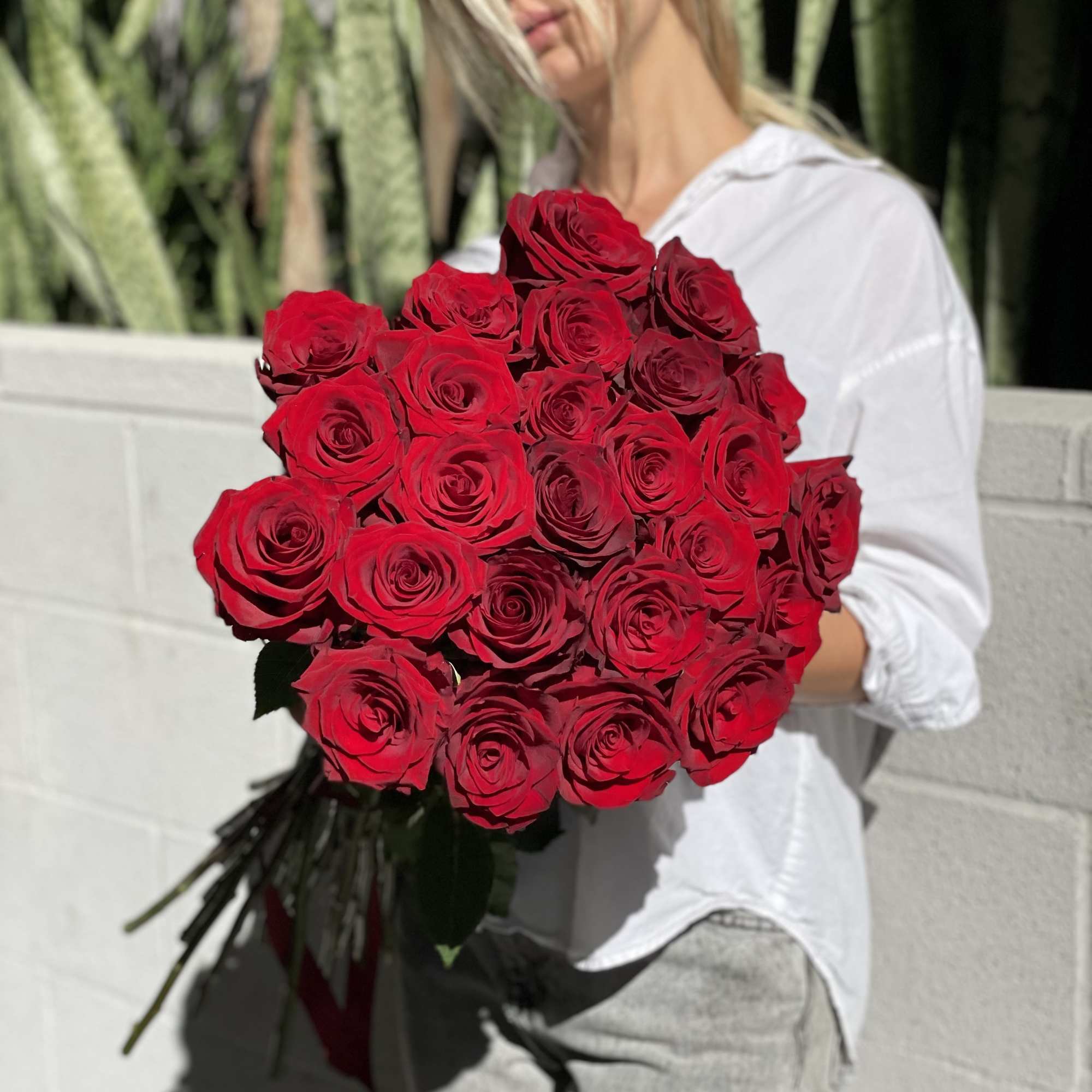Large bouquet of red roses held by a woman