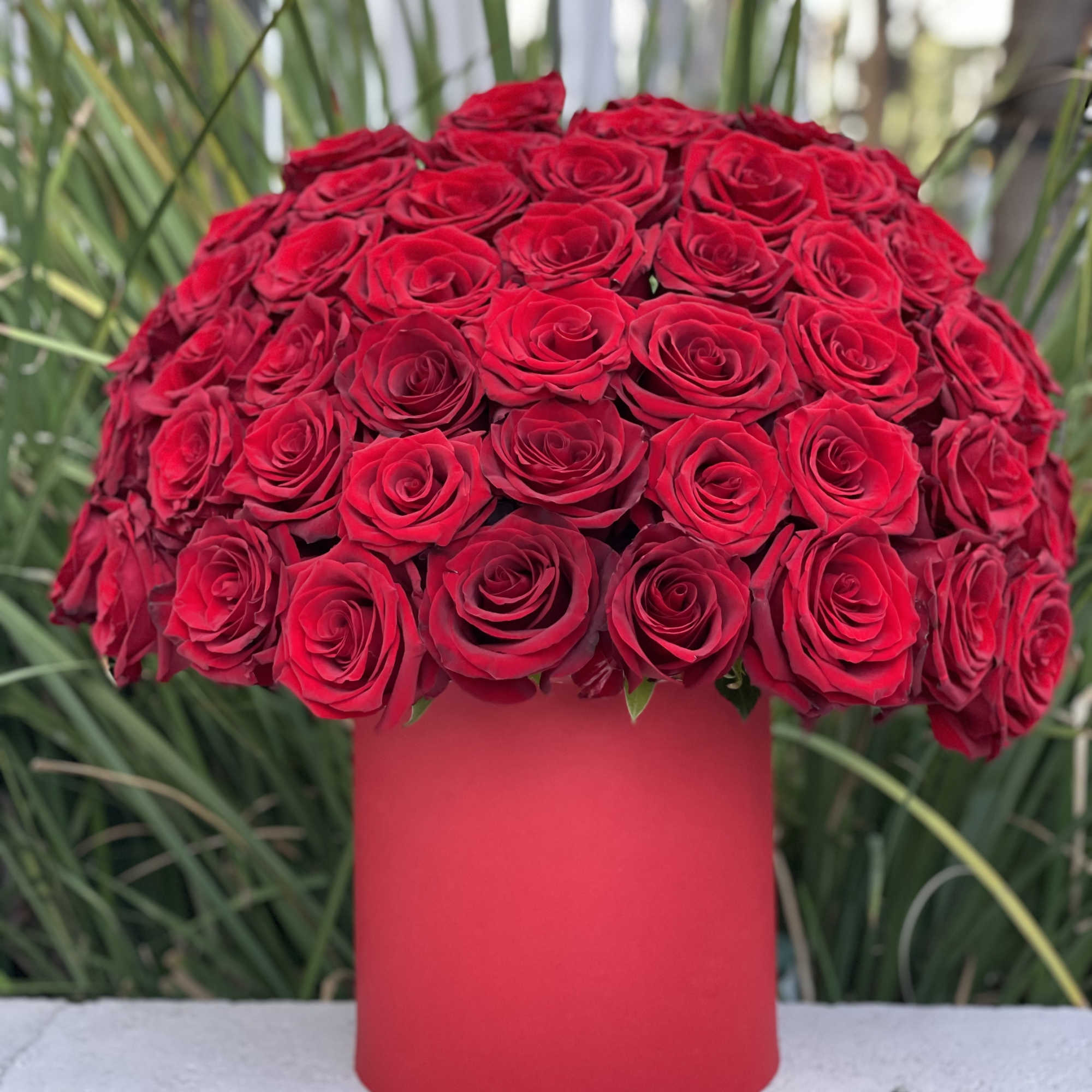 Red rose bouquet in a tall red cylindrical vase