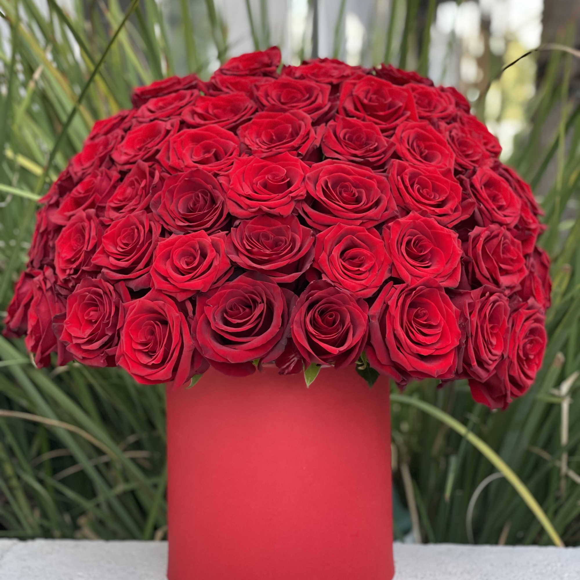 Large bouquet of red roses in a red cylindrical vase