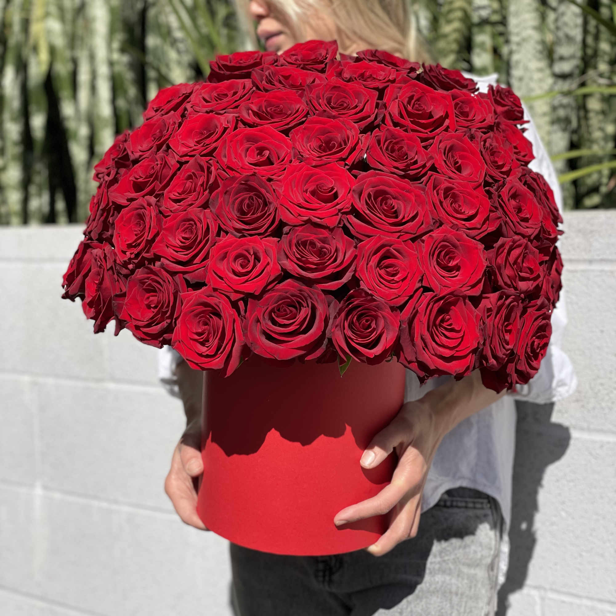 Large bouquet of red roses in a red box held by a person