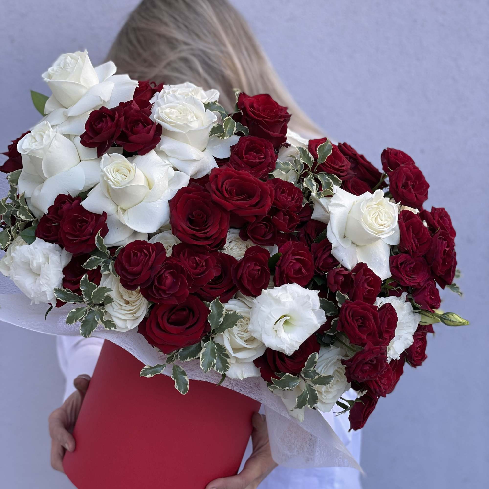 Large bouquet of red and white roses in a red hat box