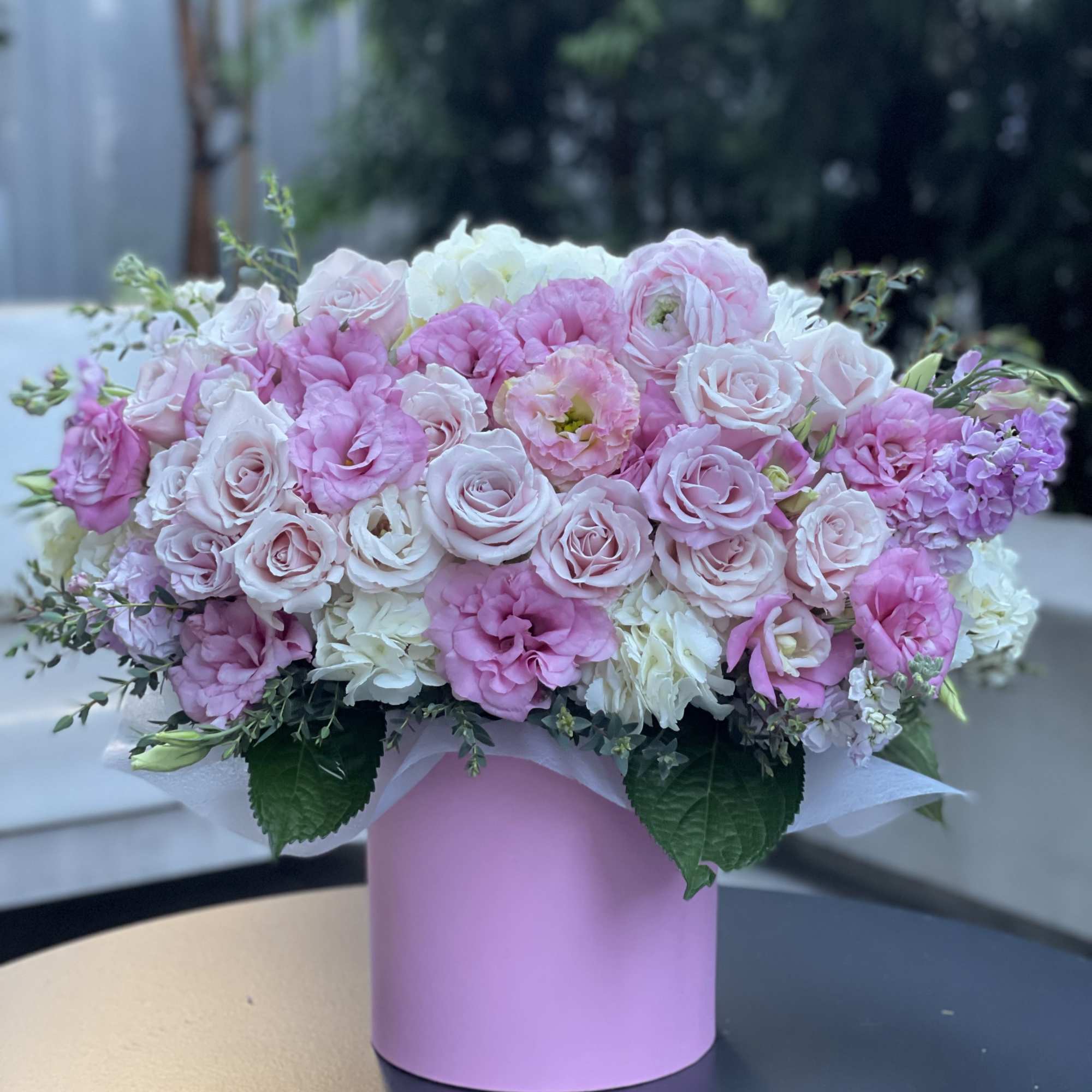 Pink and white roses arranged in a pastel pink box