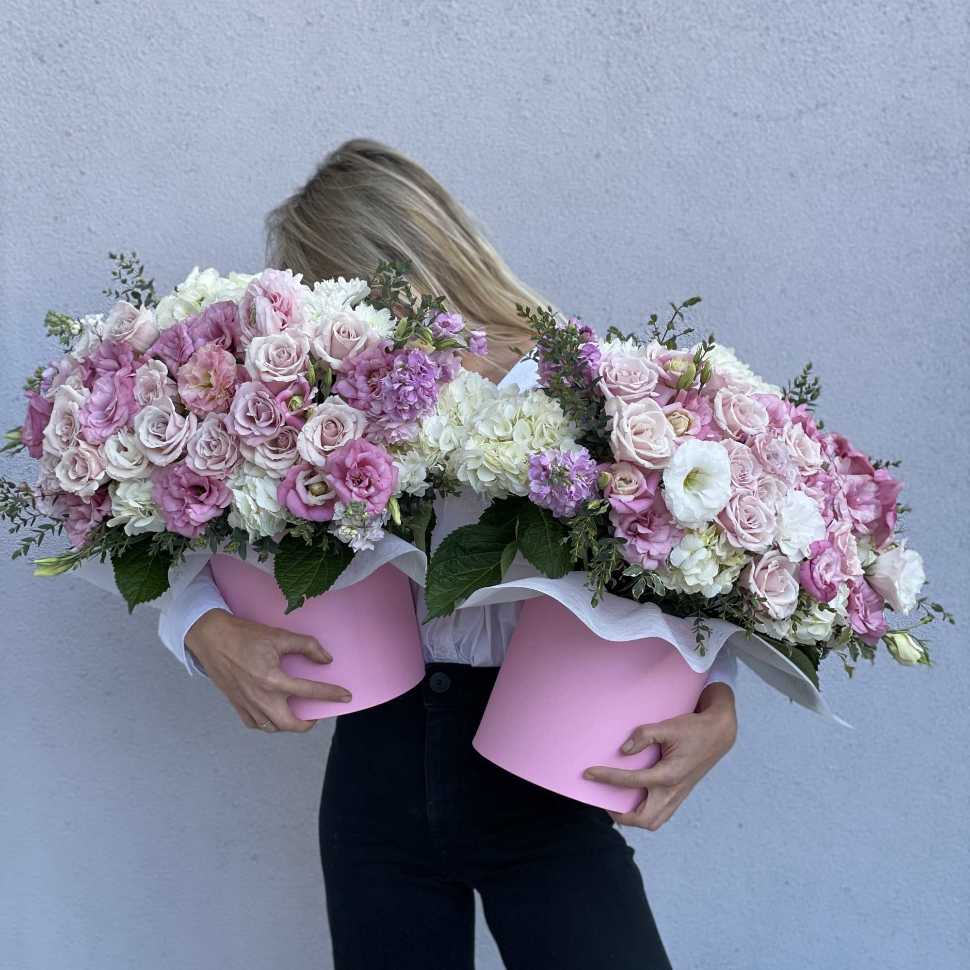 Woman holding two large pink floral arrangements in boxes