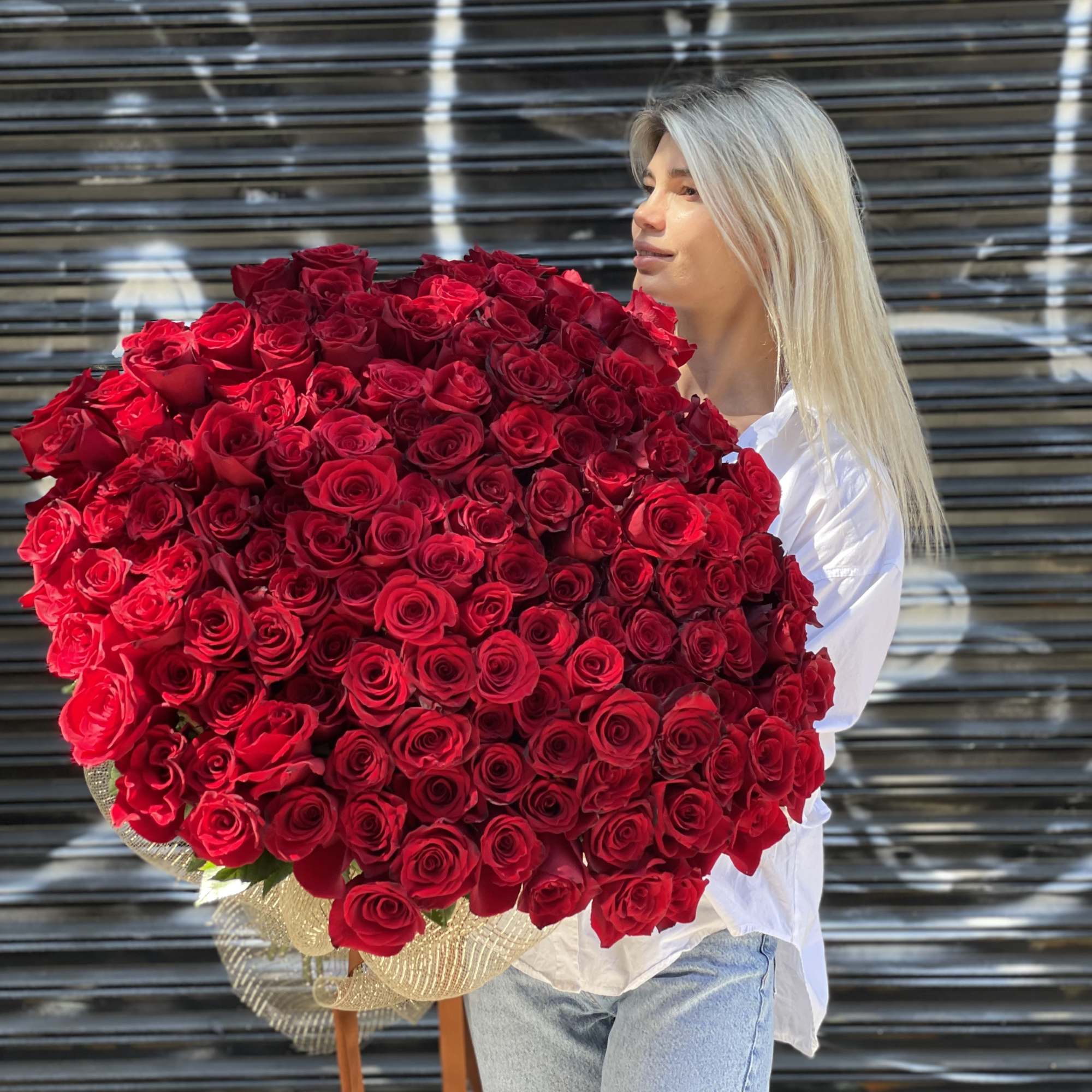 Woman holding a large bouquet of red roses