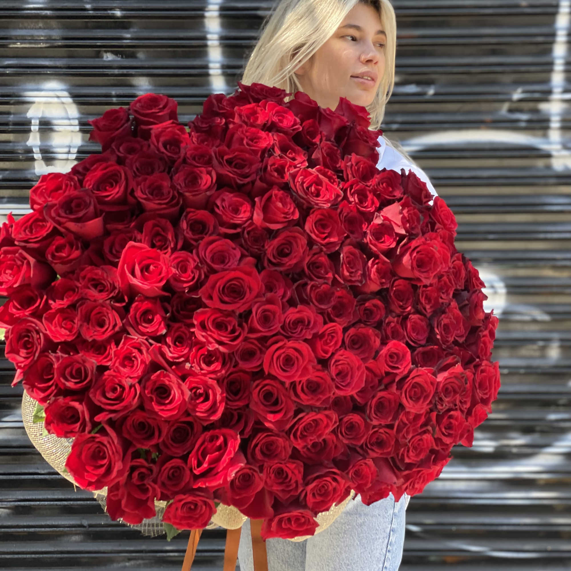Woman holding a huge bouquet of red roses
