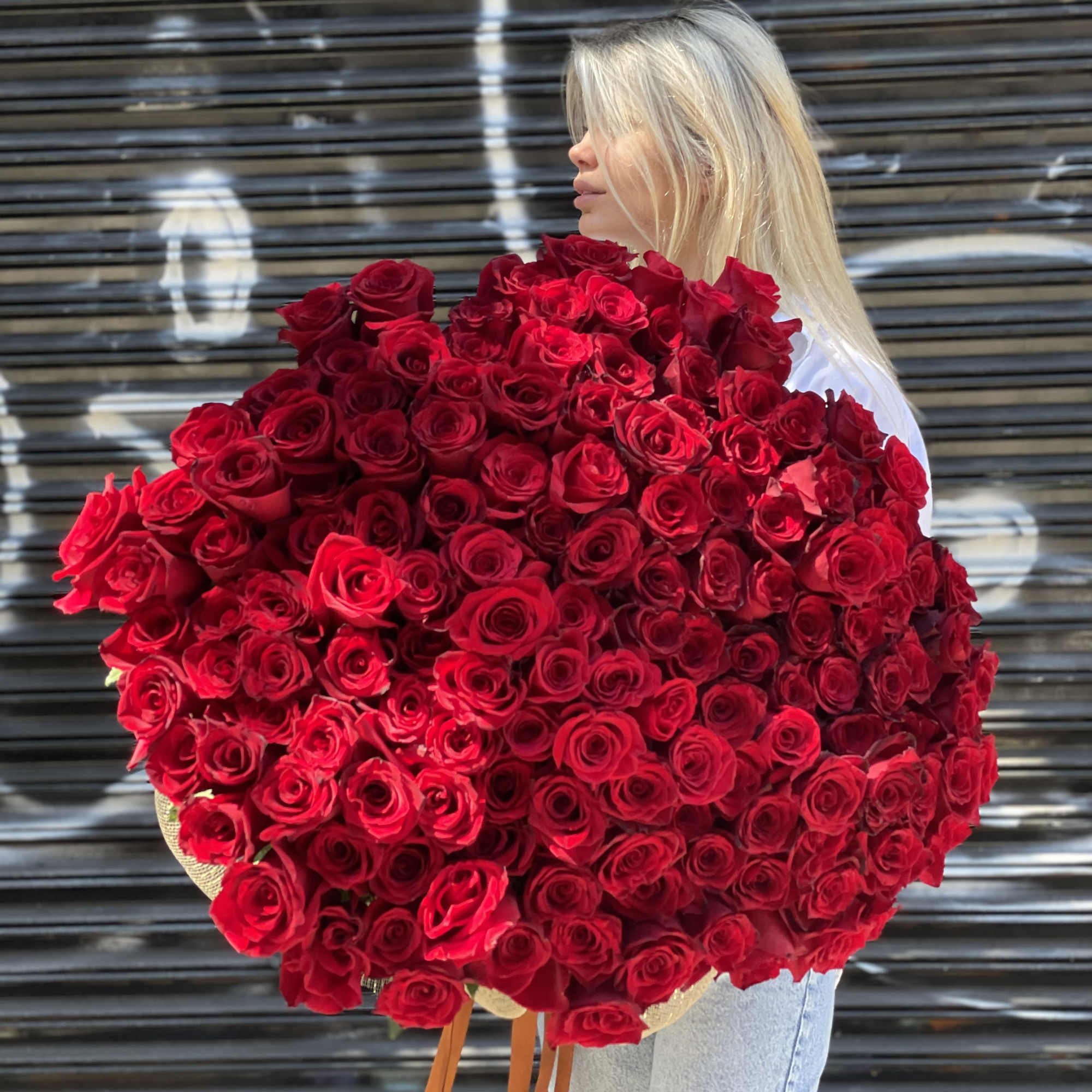 Woman holding an oversized bouquet of red roses
