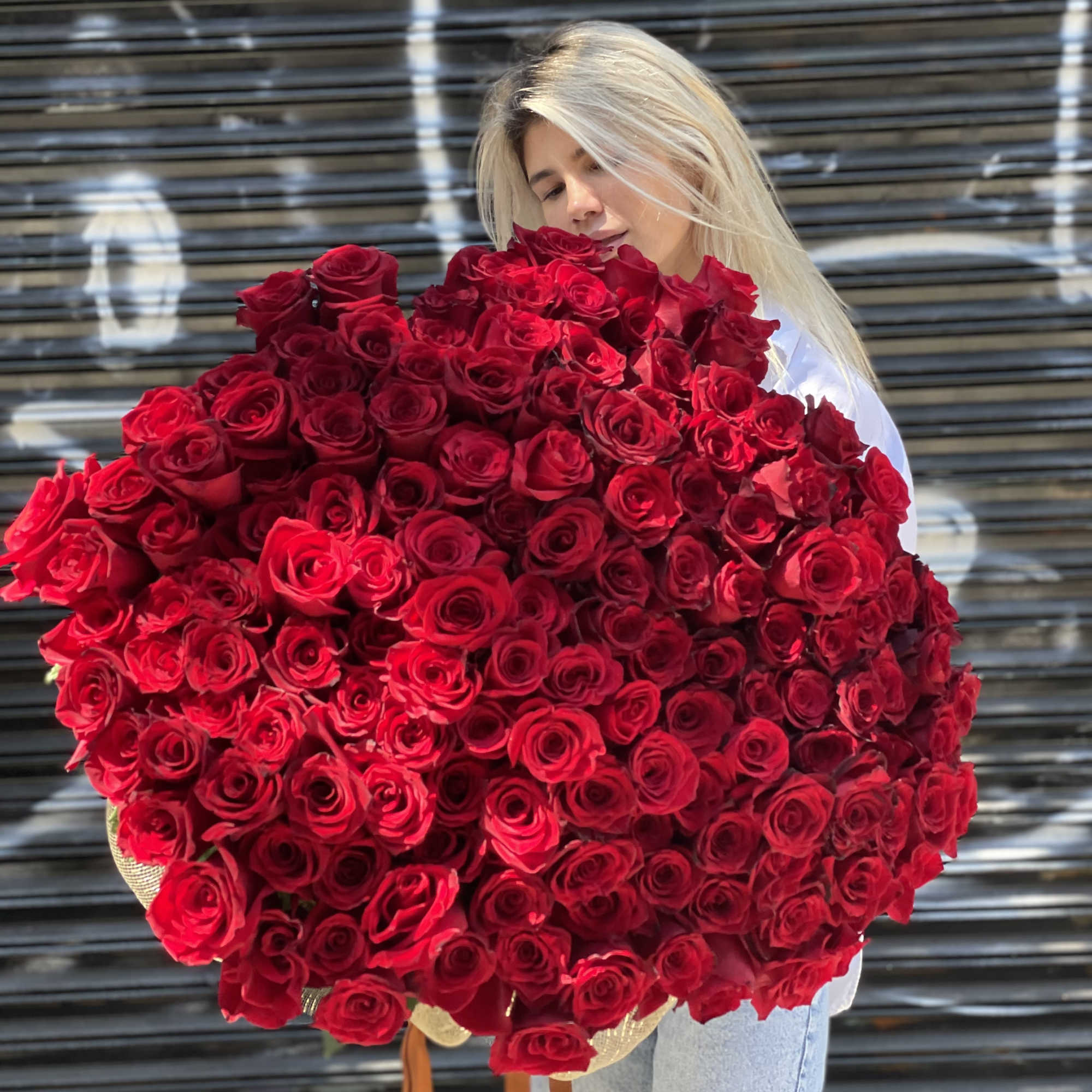 Woman holding a large bouquet of red roses, photo 4 of 6
