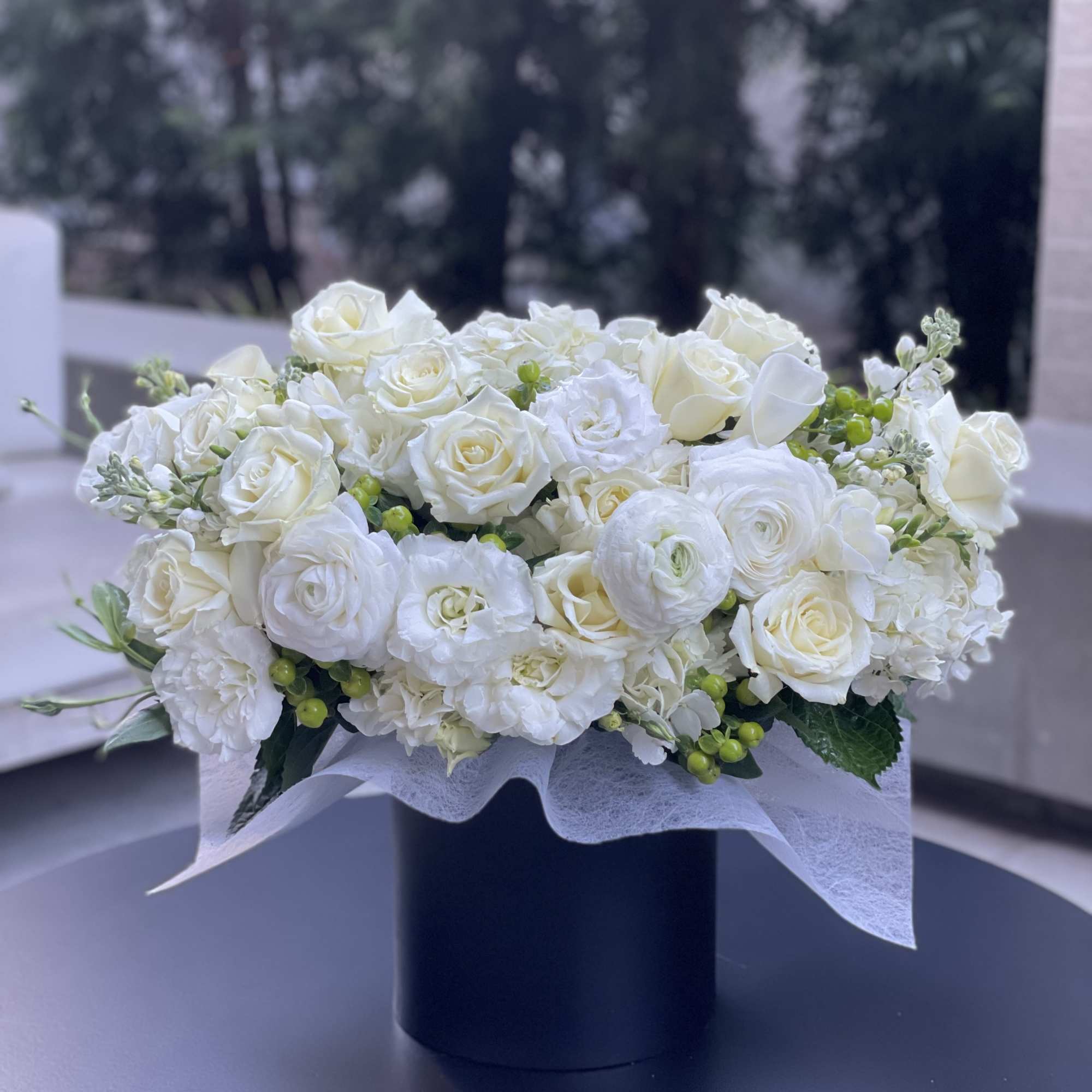 White rose and ranunculus arrangement in a black box