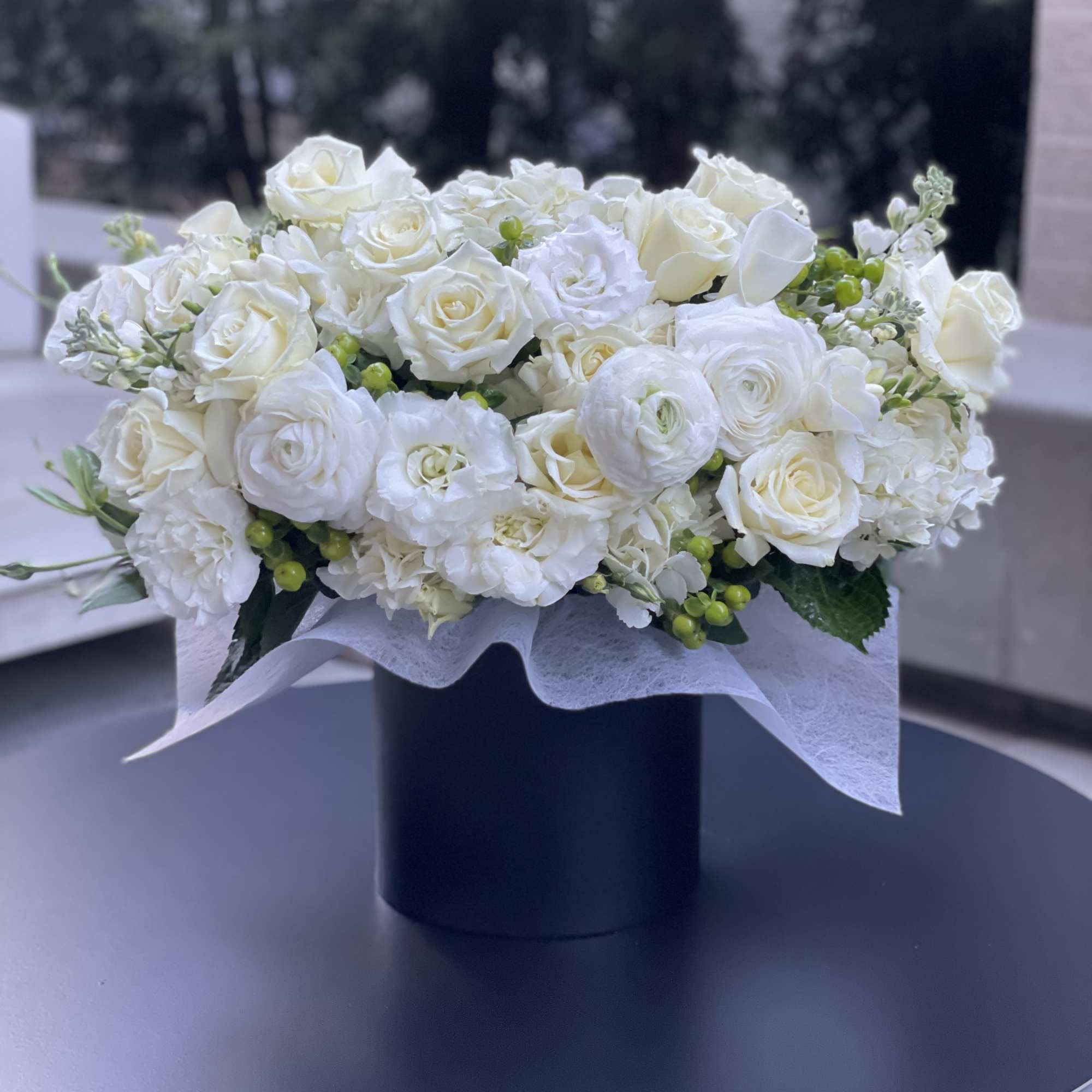 White rose bouquet in a black cylindrical vase