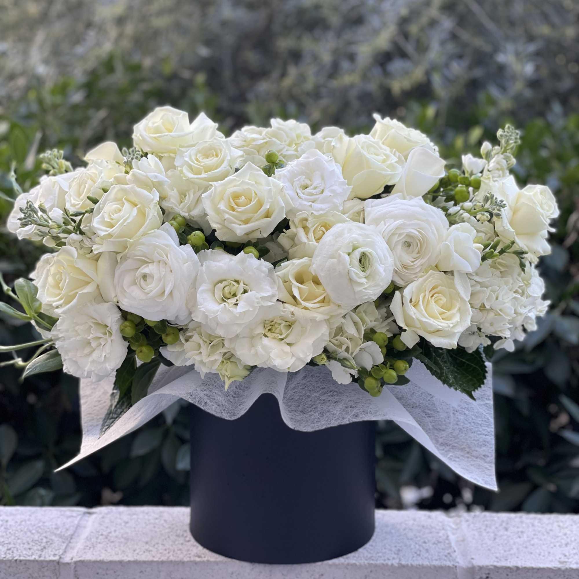 White rose and ranunculus arrangement in a black vase