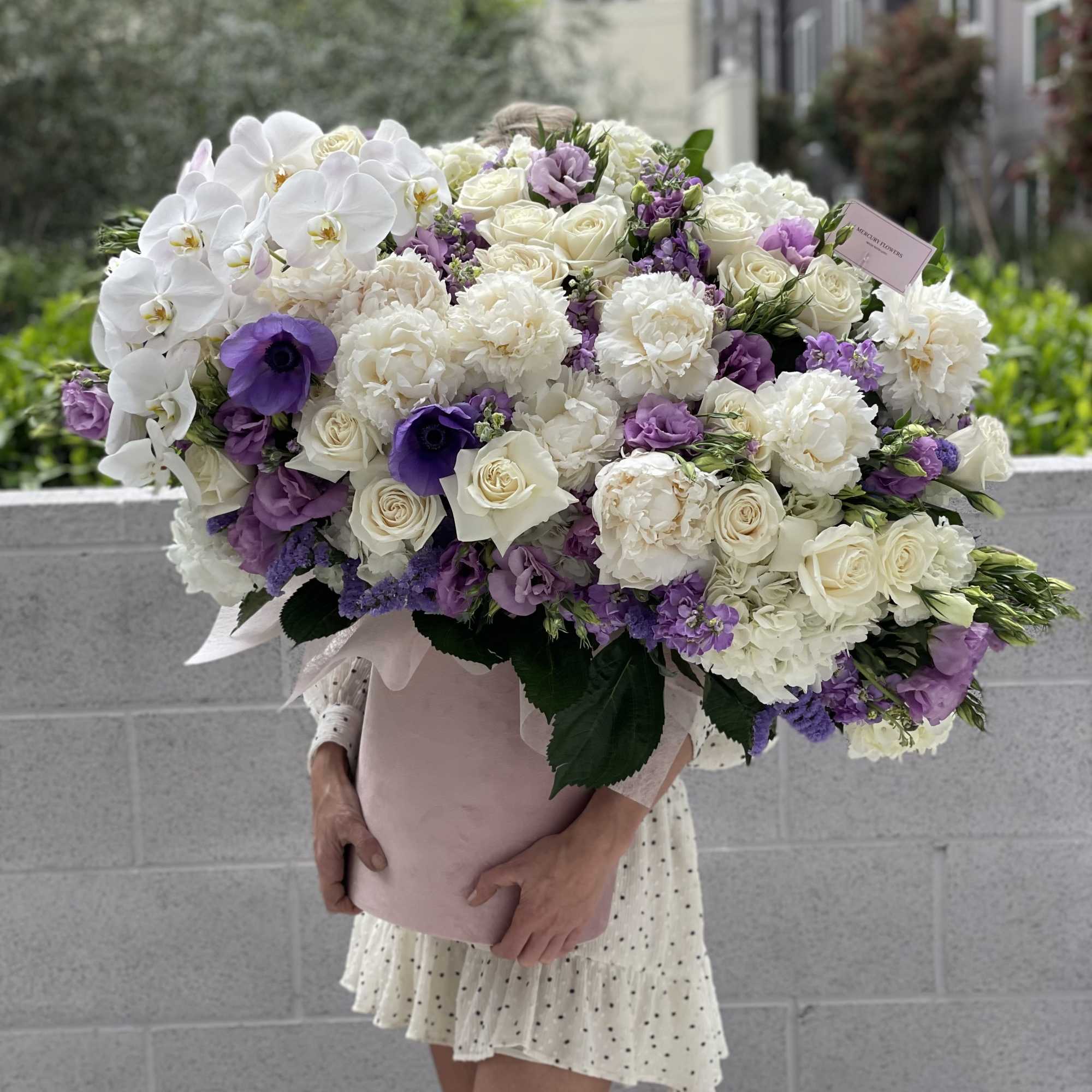 Large bouquet of white and purple flowers wrapped in pink paper