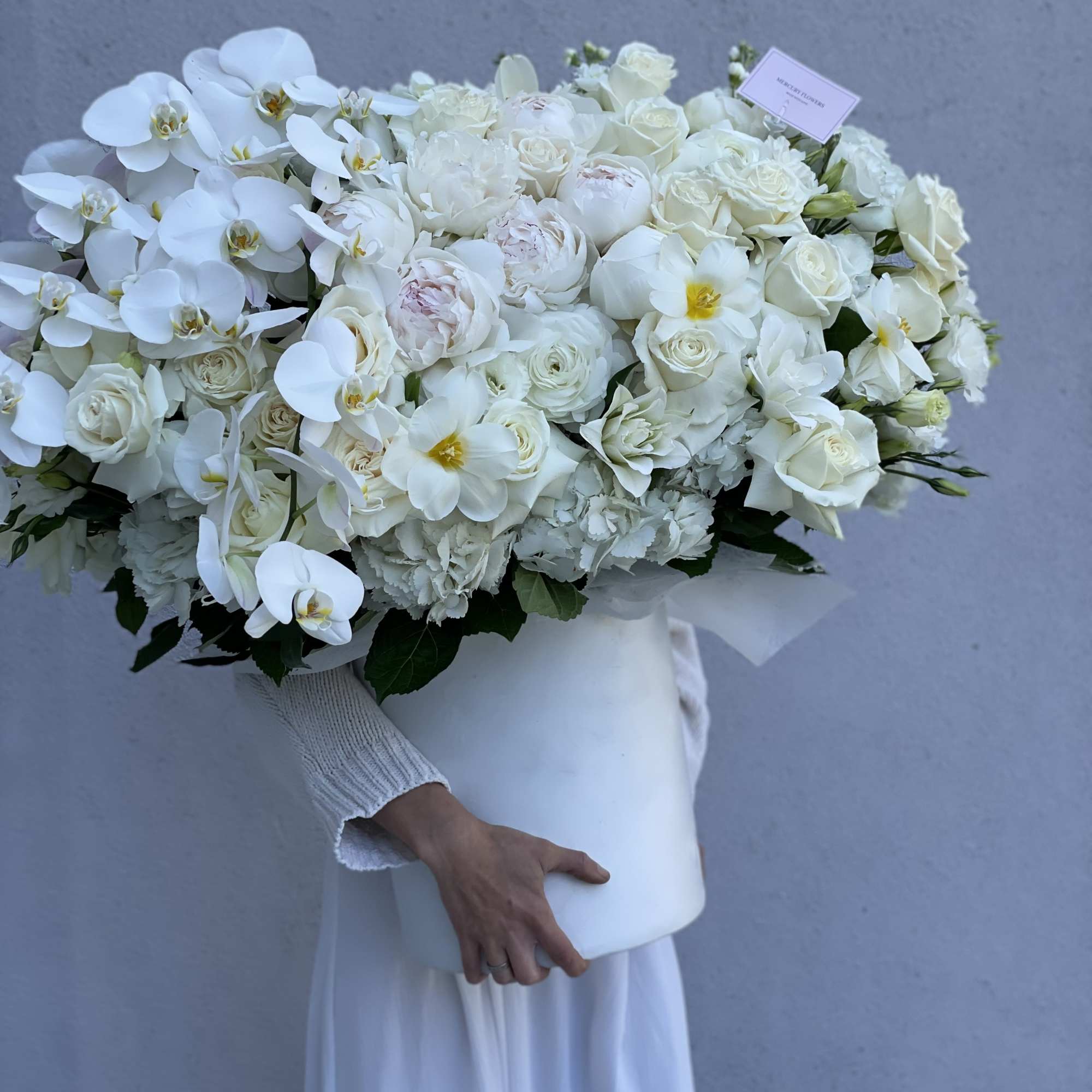 Large white bouquet with orchids and roses in a white box