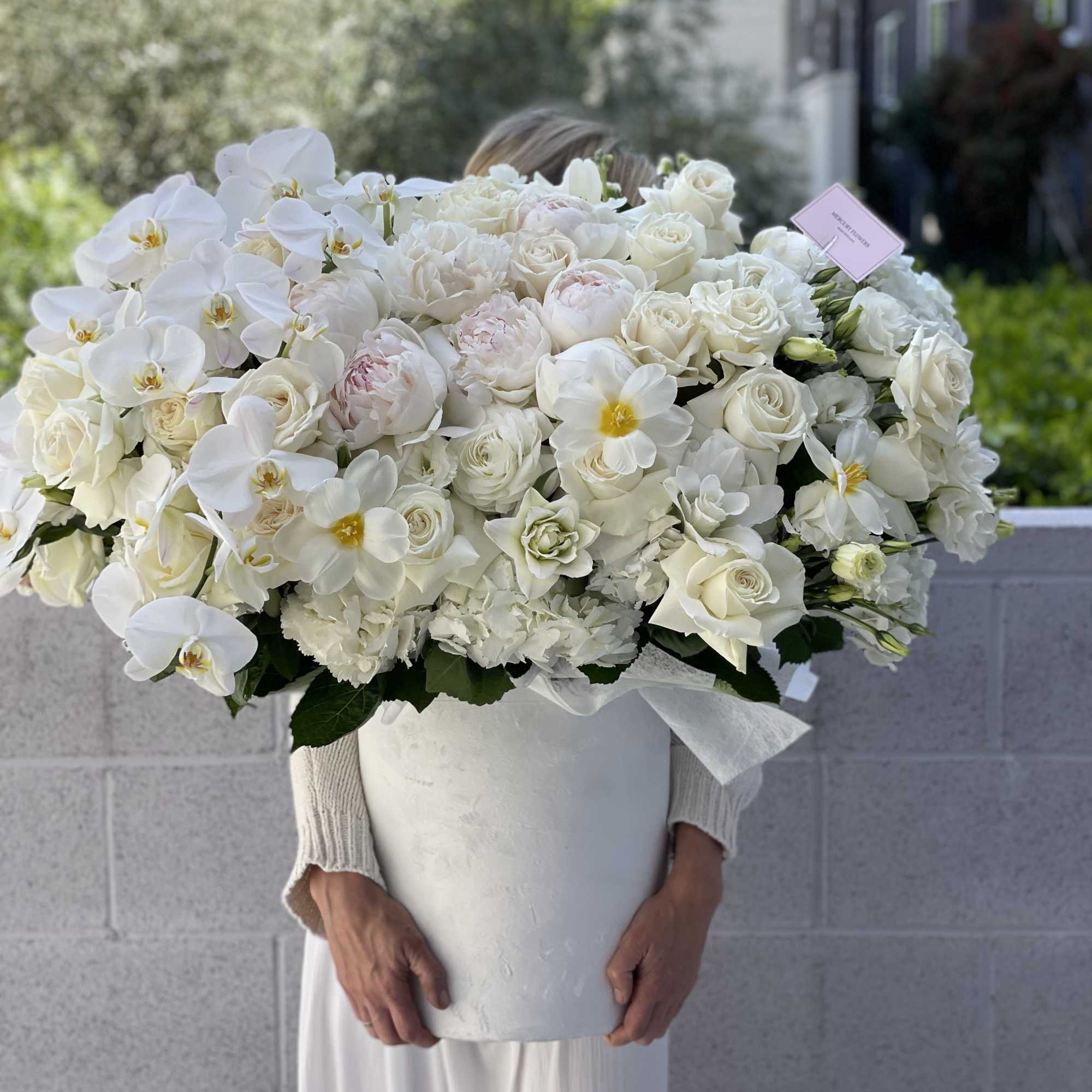 Large white floral arrangement in a tall white vase