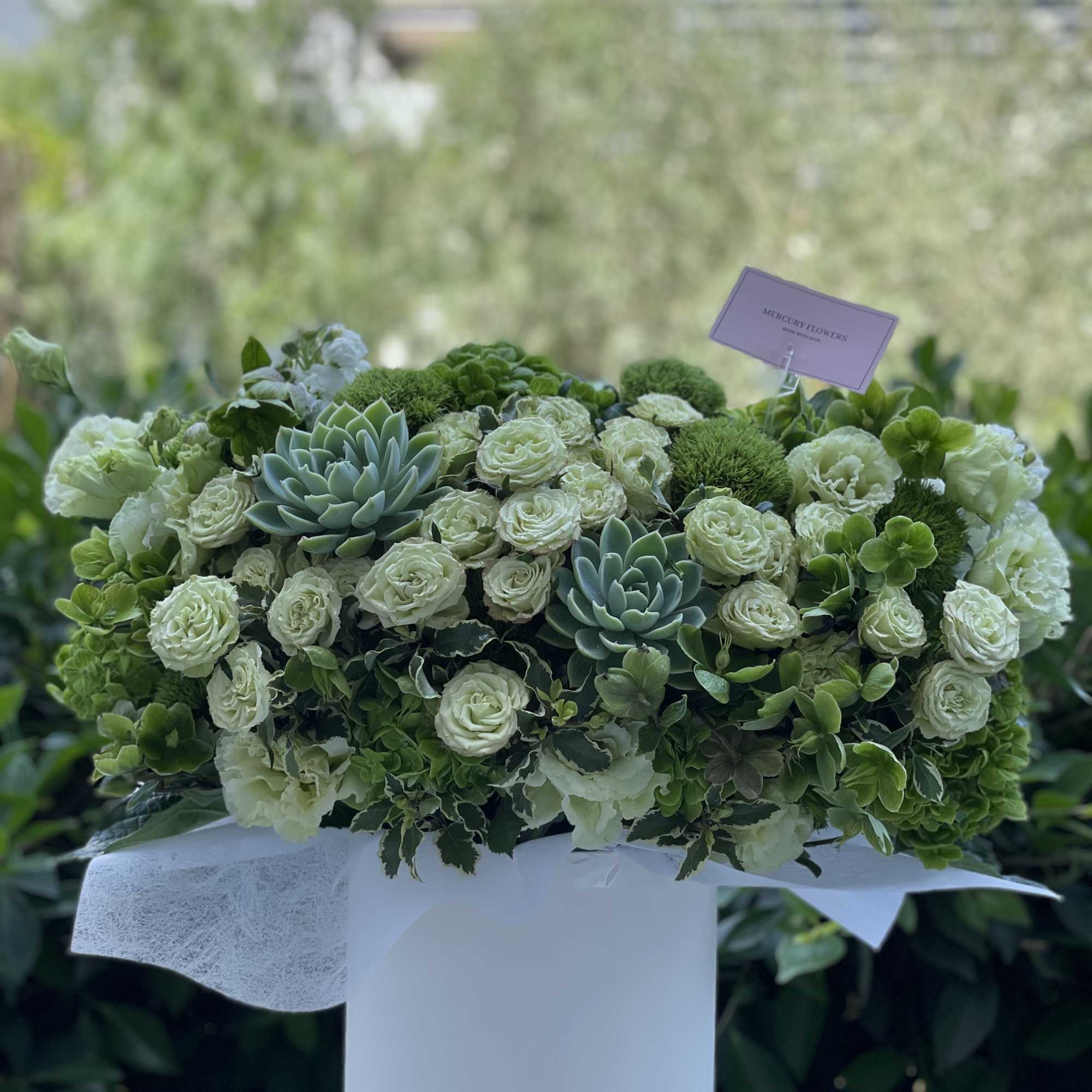 Green and white floral arrangement in a white cylindrical vase, photo 7 of 10