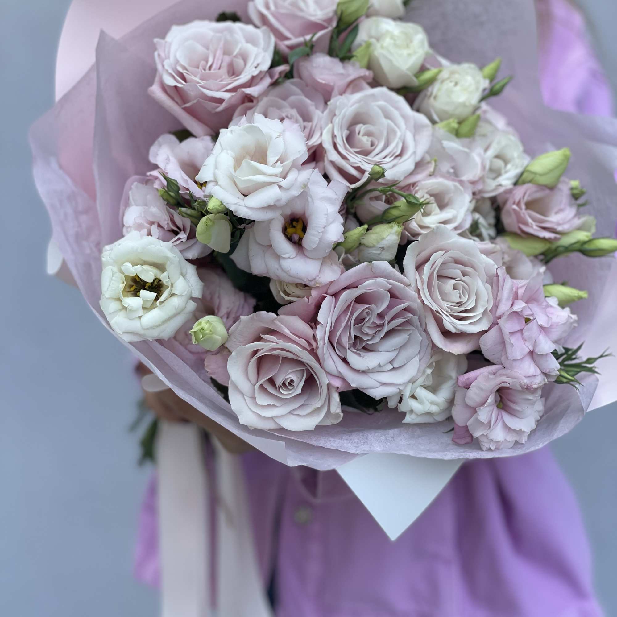 Bouquet of pale pink and white roses wrapped in lavender paper