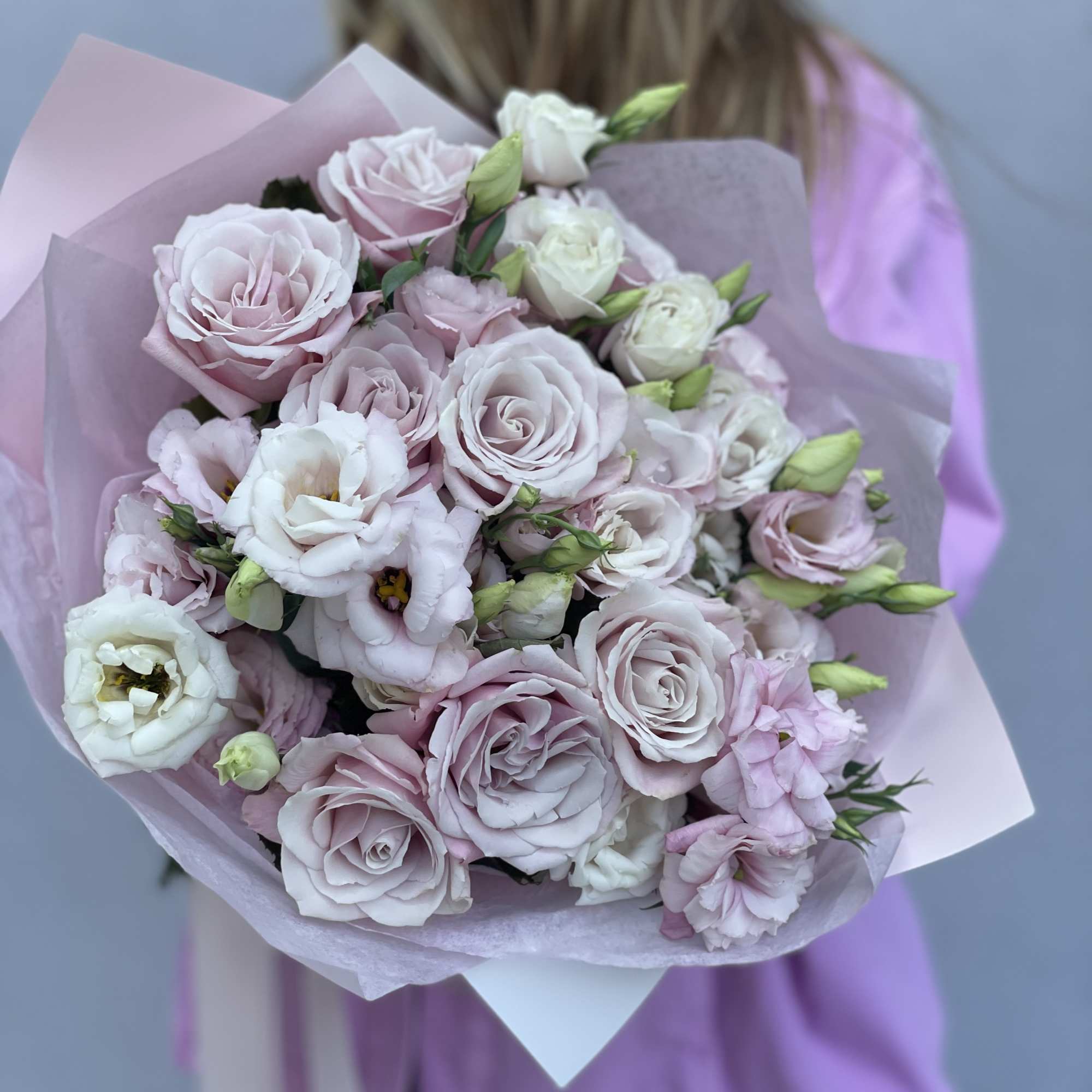 Handheld bouquet of pale pink and white roses with soft wrapping