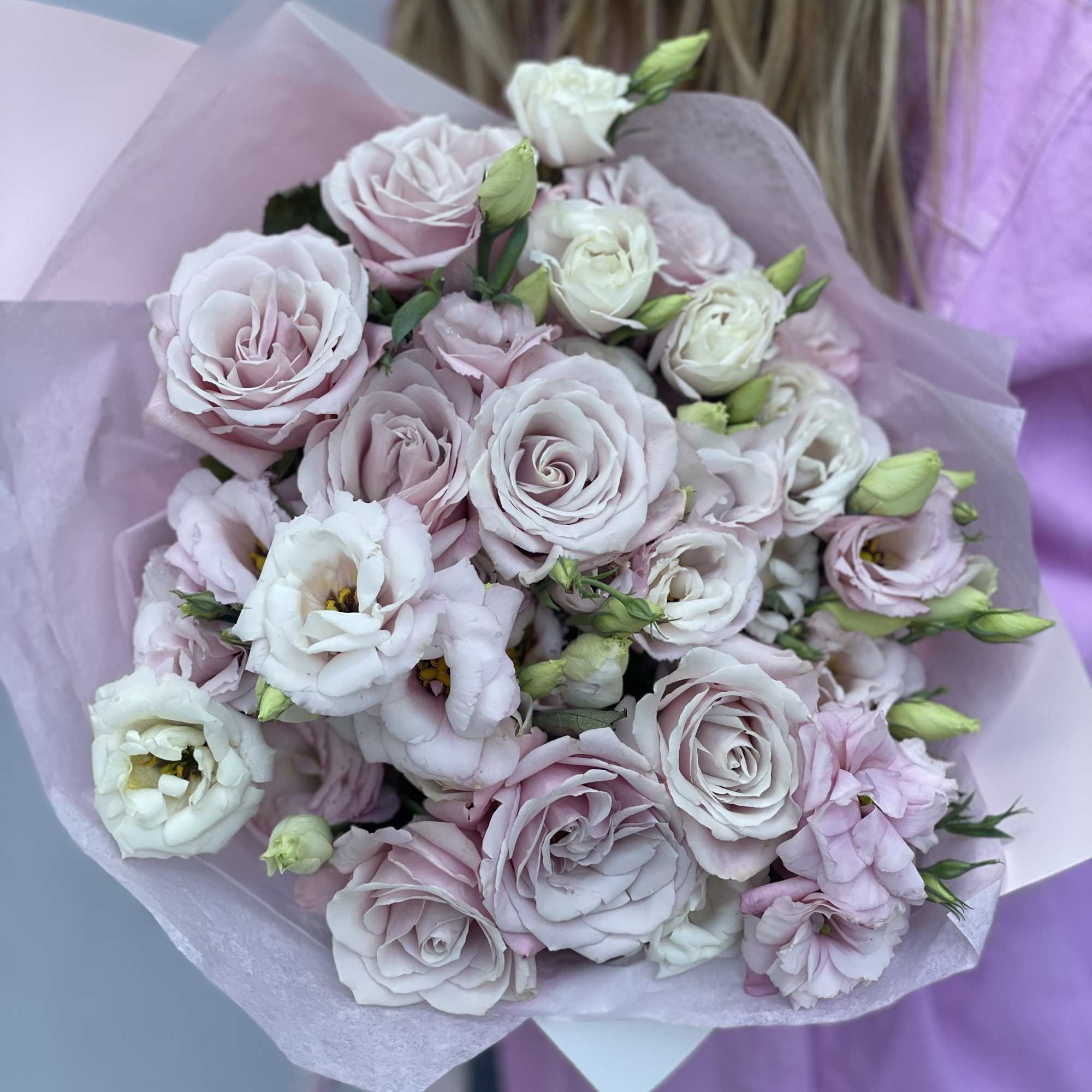 Bouquet of pale pink roses and white lisianthus wrapped in pink paper