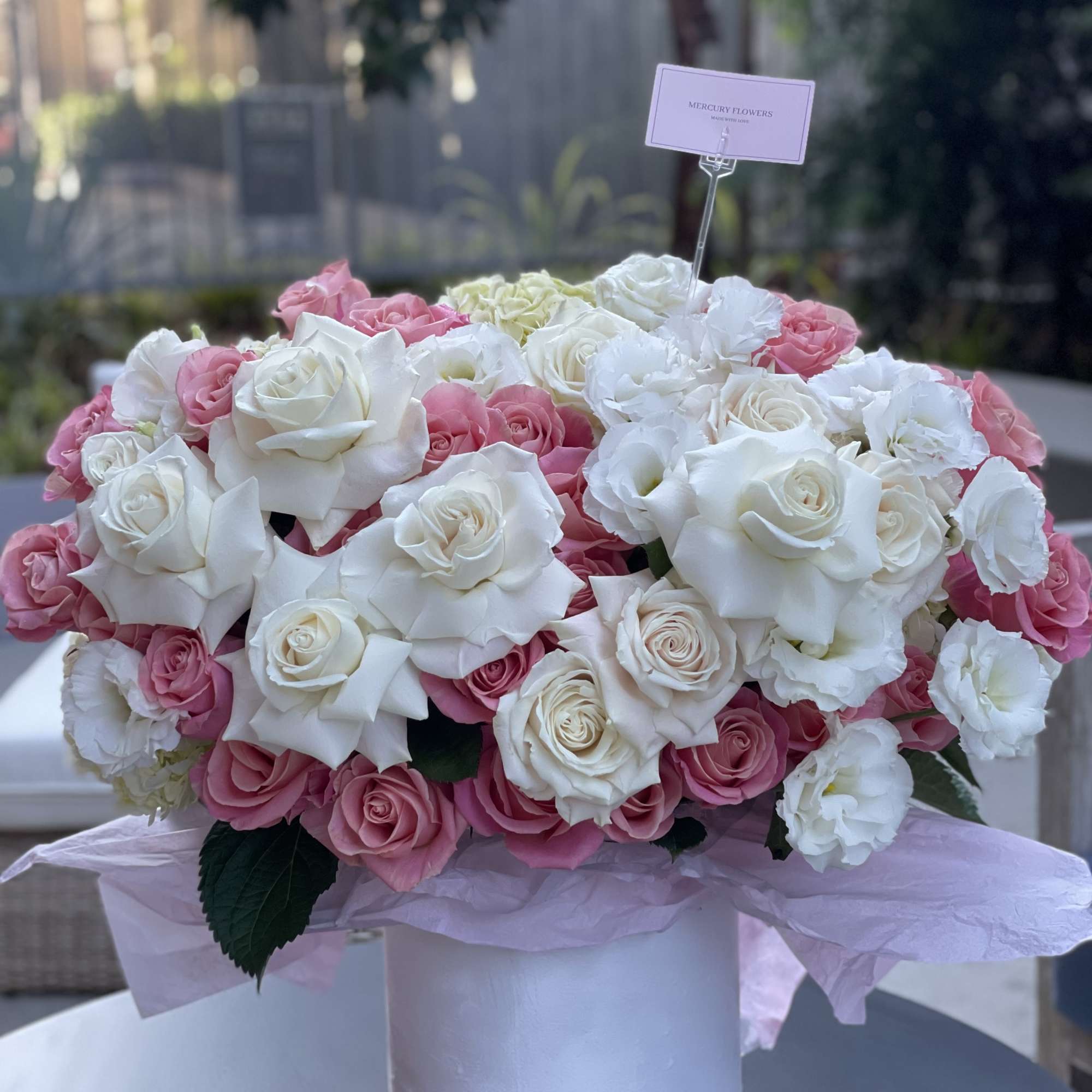 Pink and white rose arrangement in a white hatbox