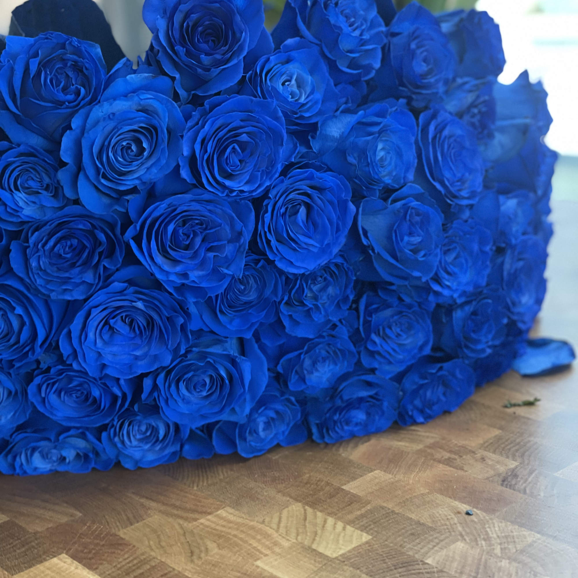 Large bouquet of vivid blue roses on a wooden surface