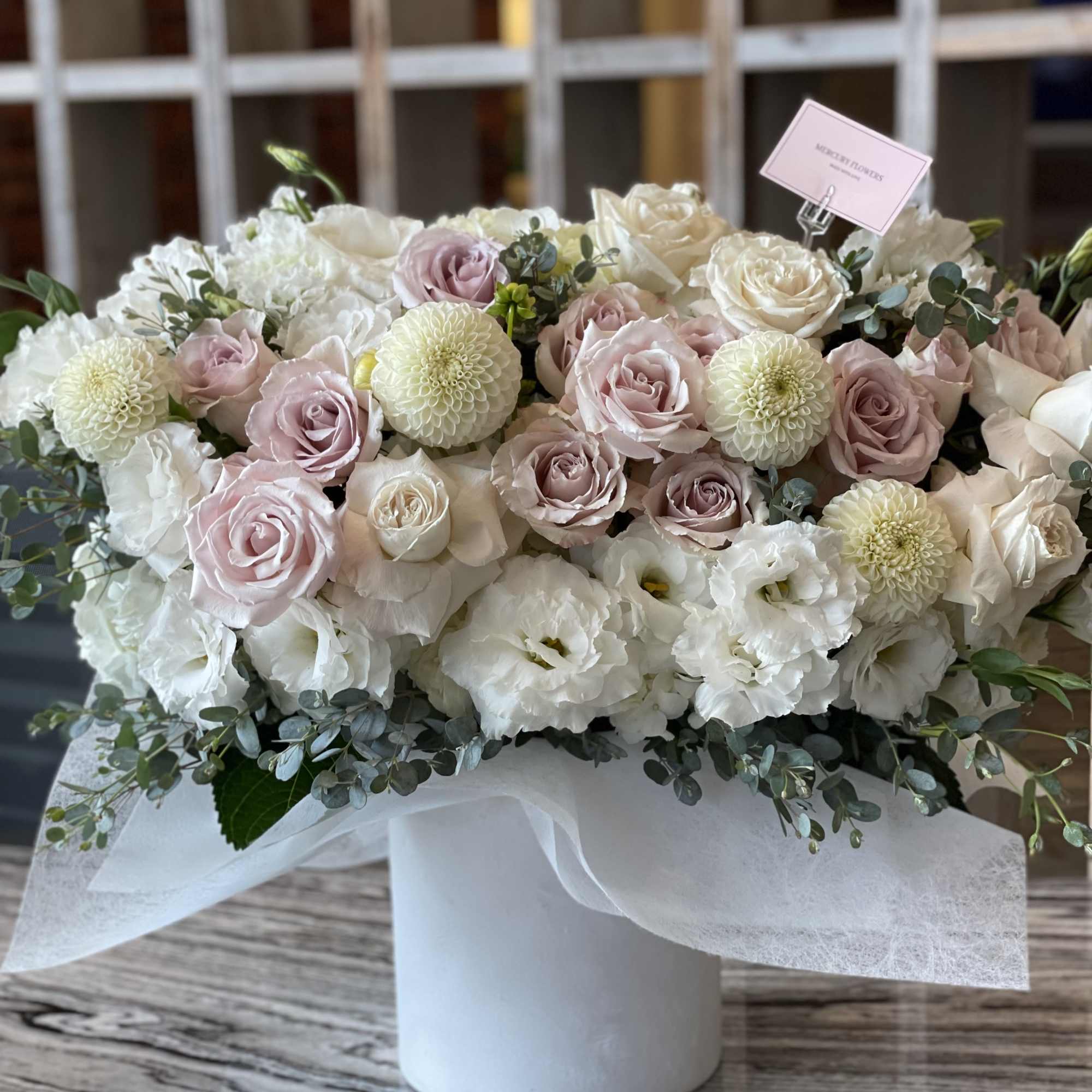 Bouquet of pale pink and white roses with white blooms in a white box