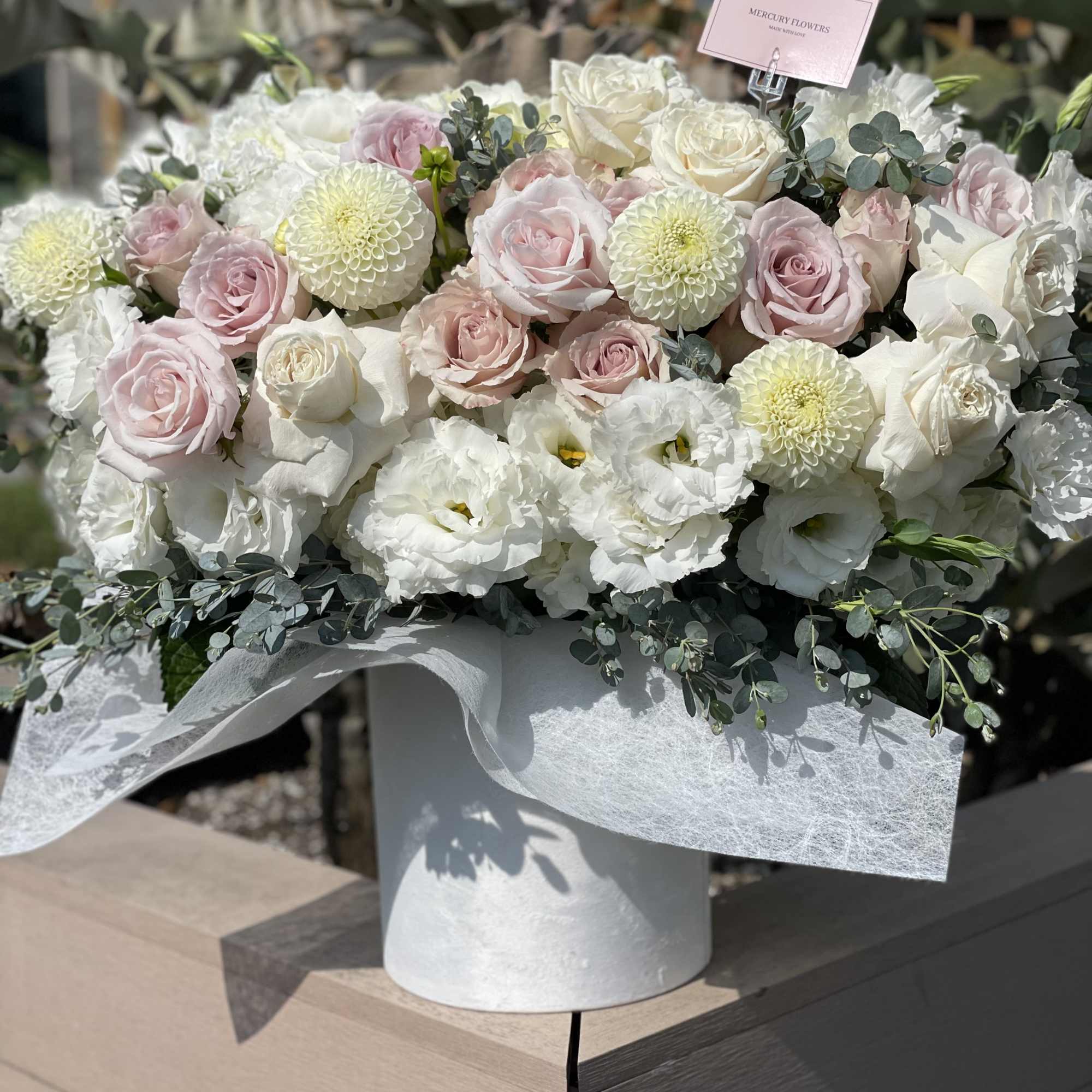 Large bouquet of white and blush roses with white blooms in a white vase