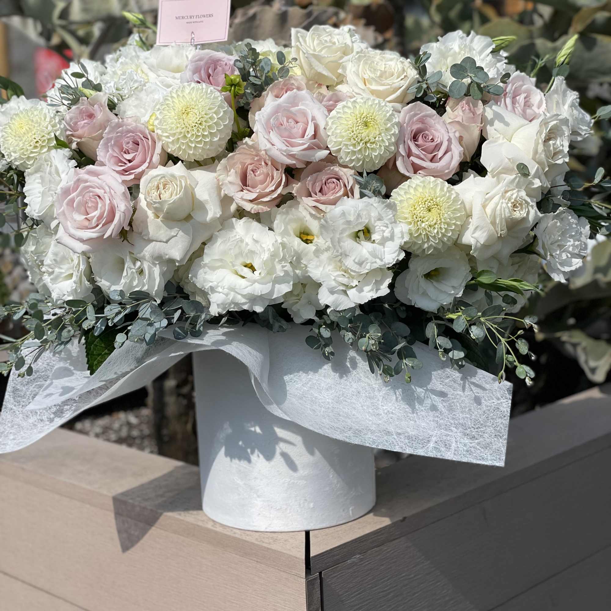 White and blush roses arranged in a round white box