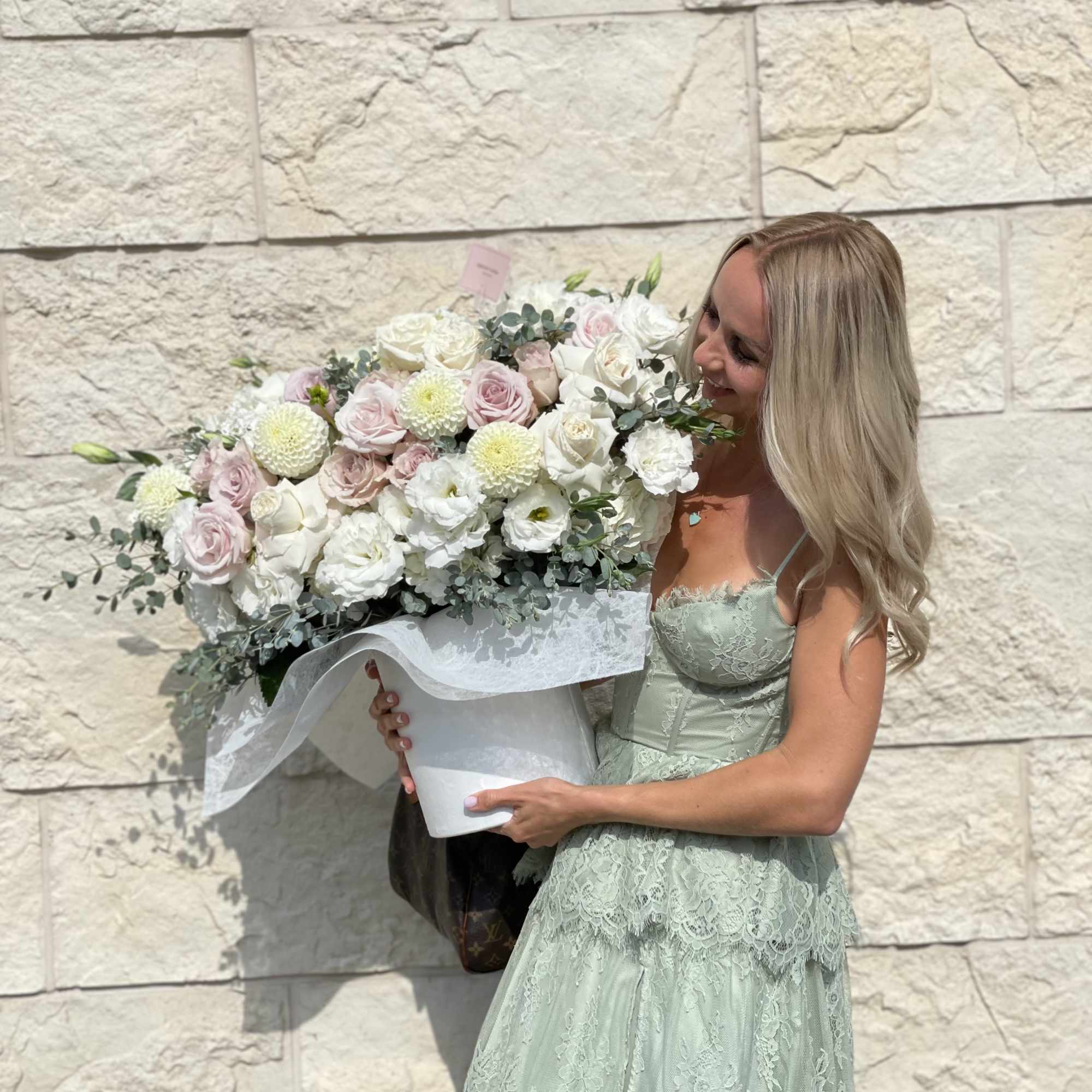 Woman holding a large bouquet of pale pink and white flowers, photo 8 of 9