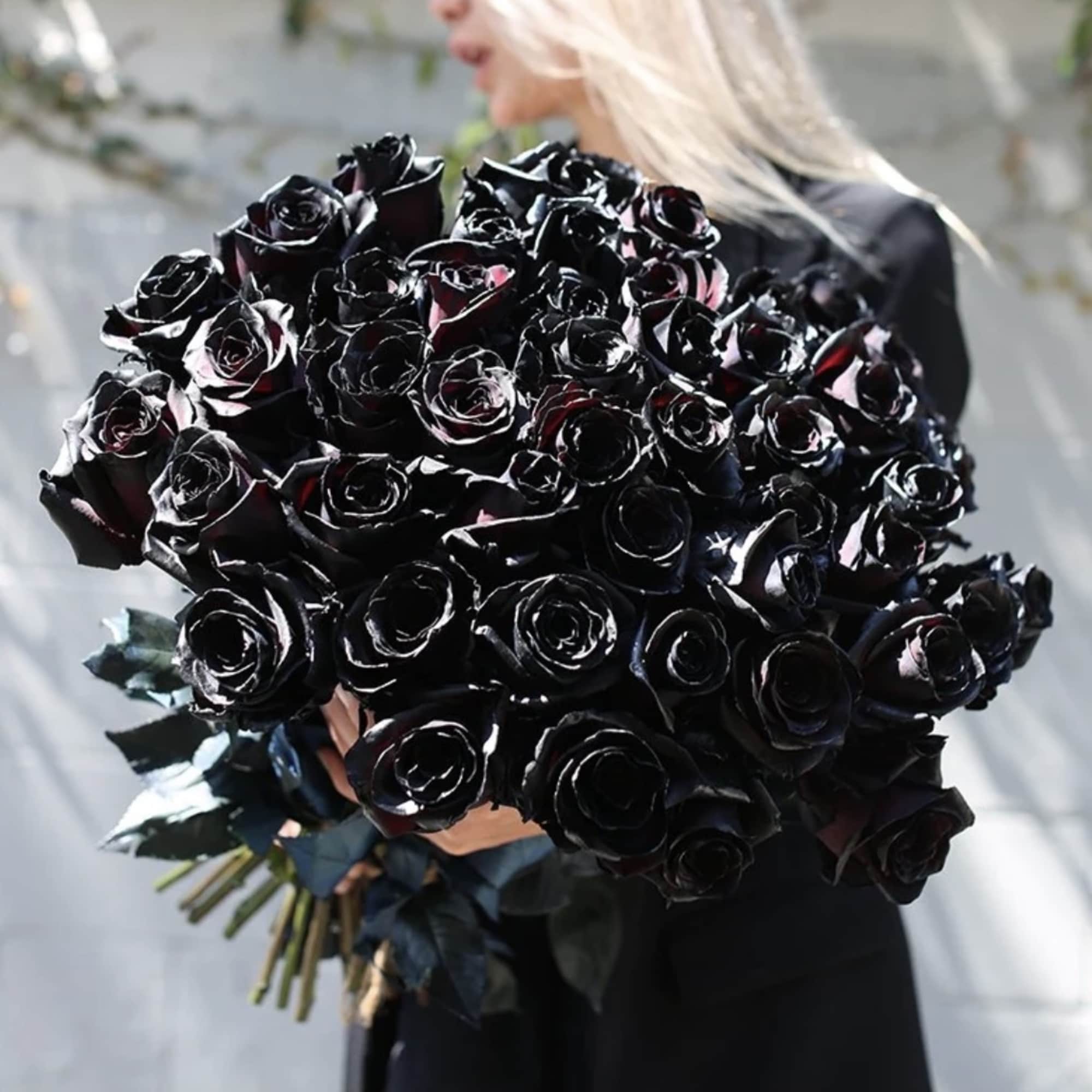 Large bouquet of black roses held by a person in dark clothing