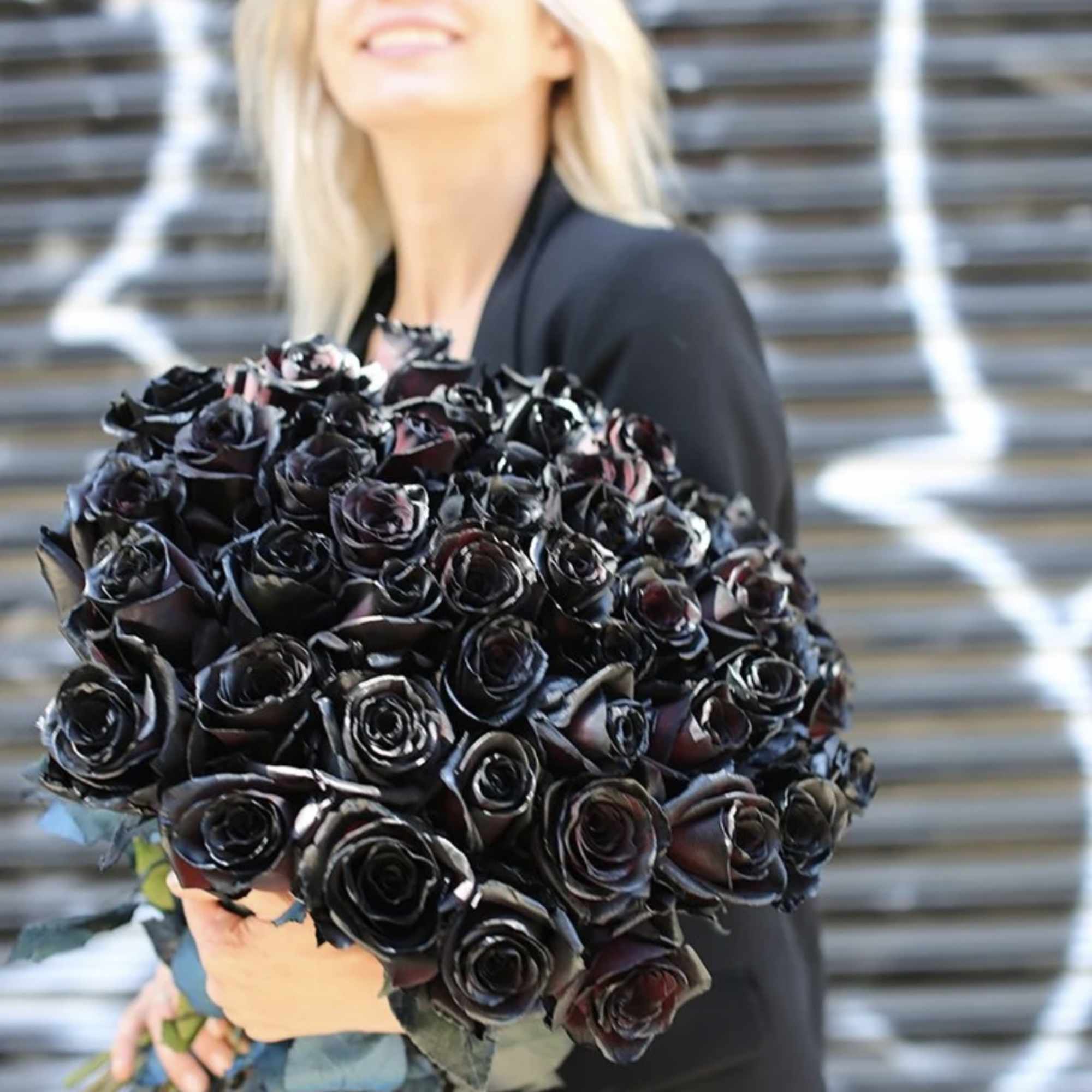 Woman holding a large bouquet of dark roses