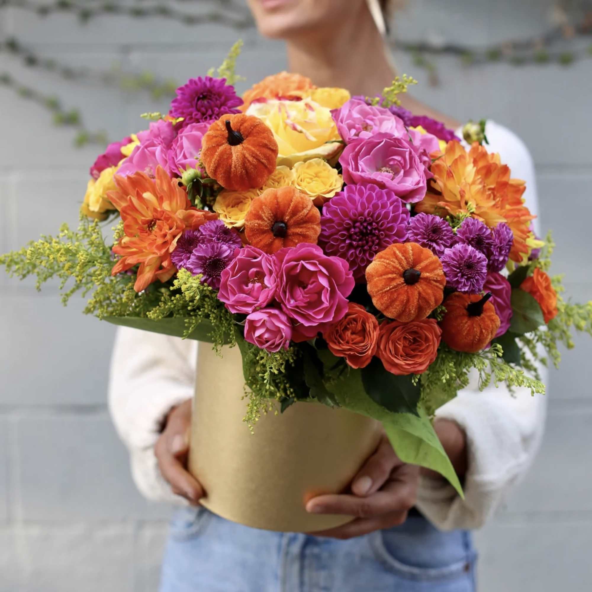 Bright mixed bouquet in a gold box with pink, orange, yellow, and purple flowers