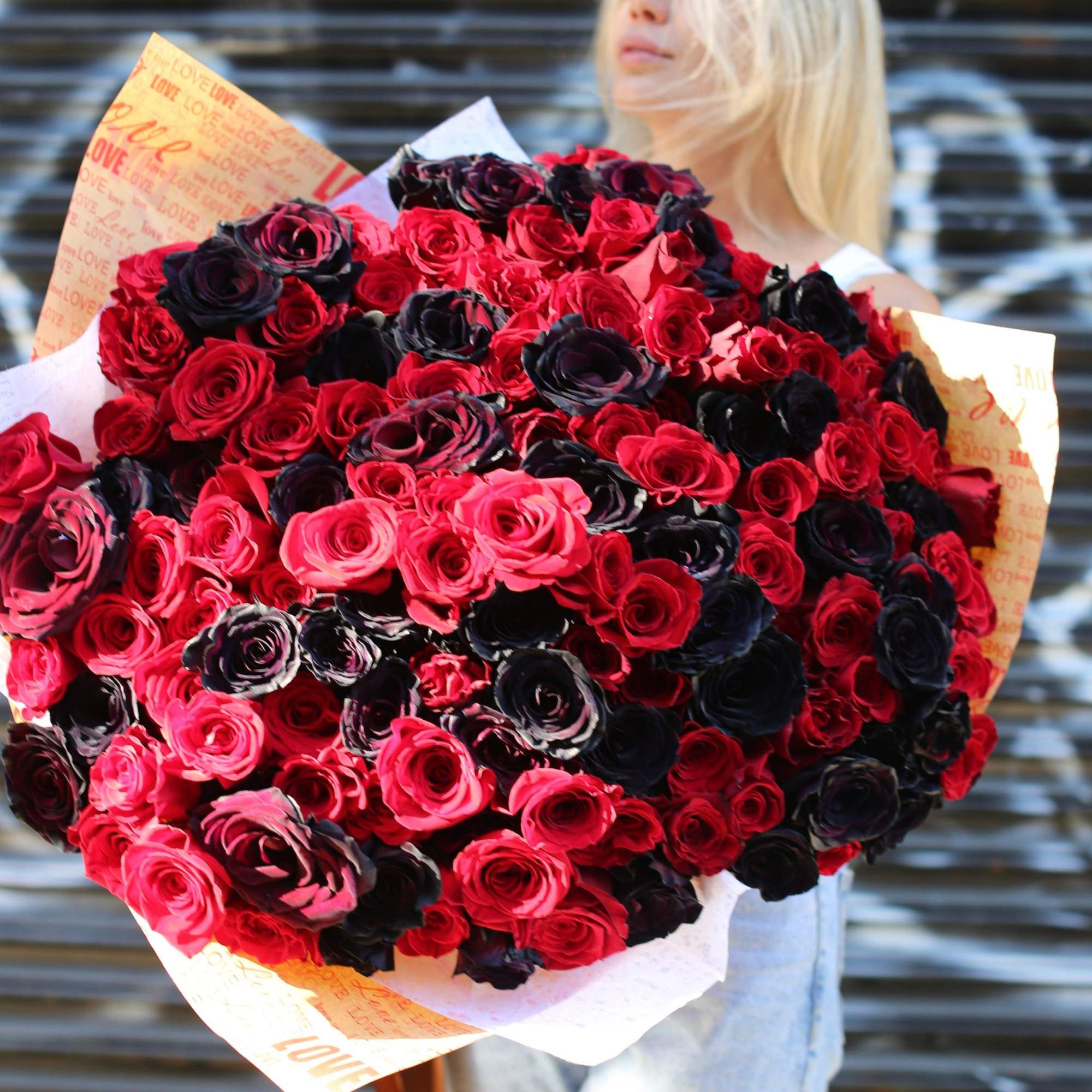 Large bouquet of red, pink, and dark roses wrapped in printed paper, photo 2 of 2