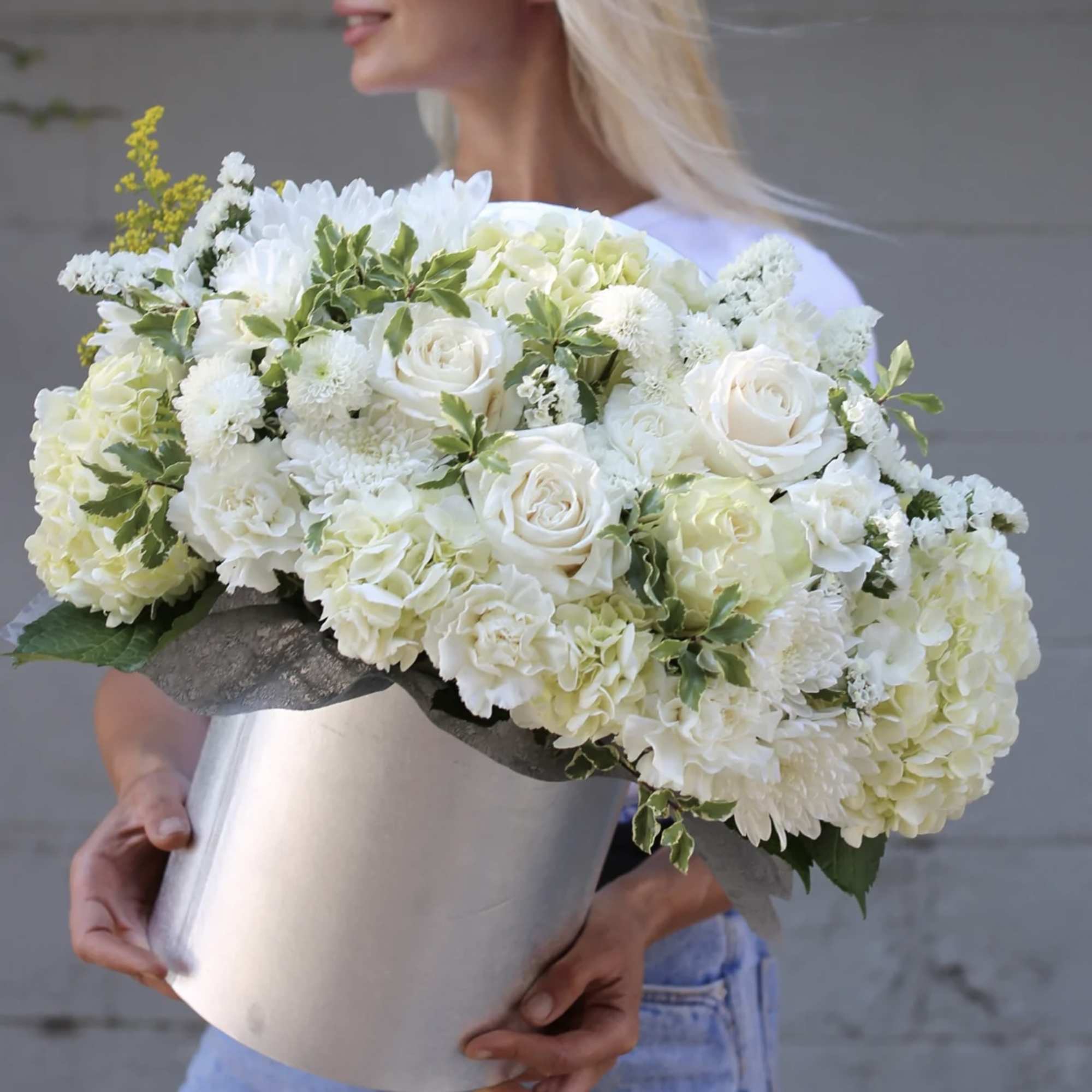 Woman holding a large white bouquet in a silver box