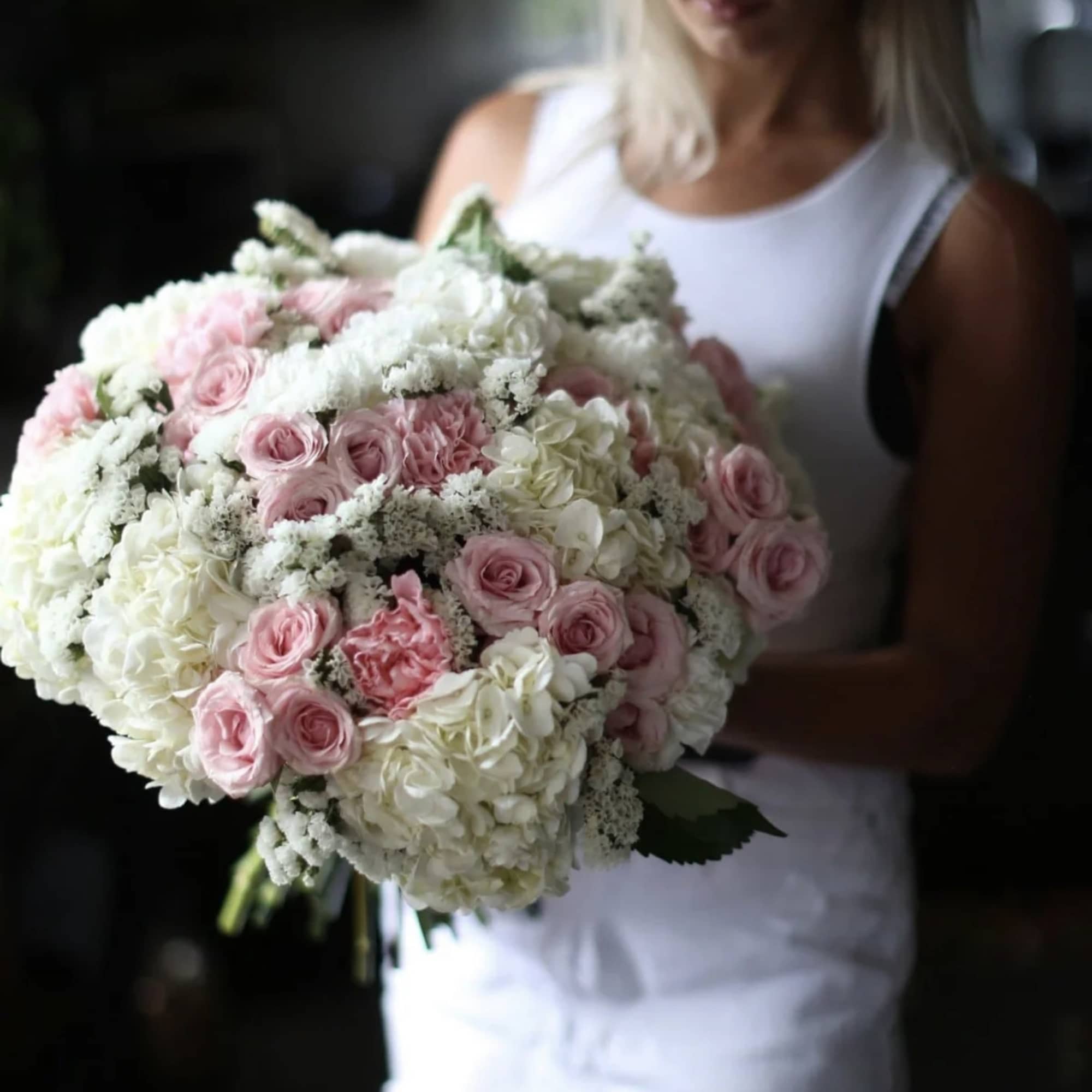 Woman holding a large bouquet of pink and white flowers