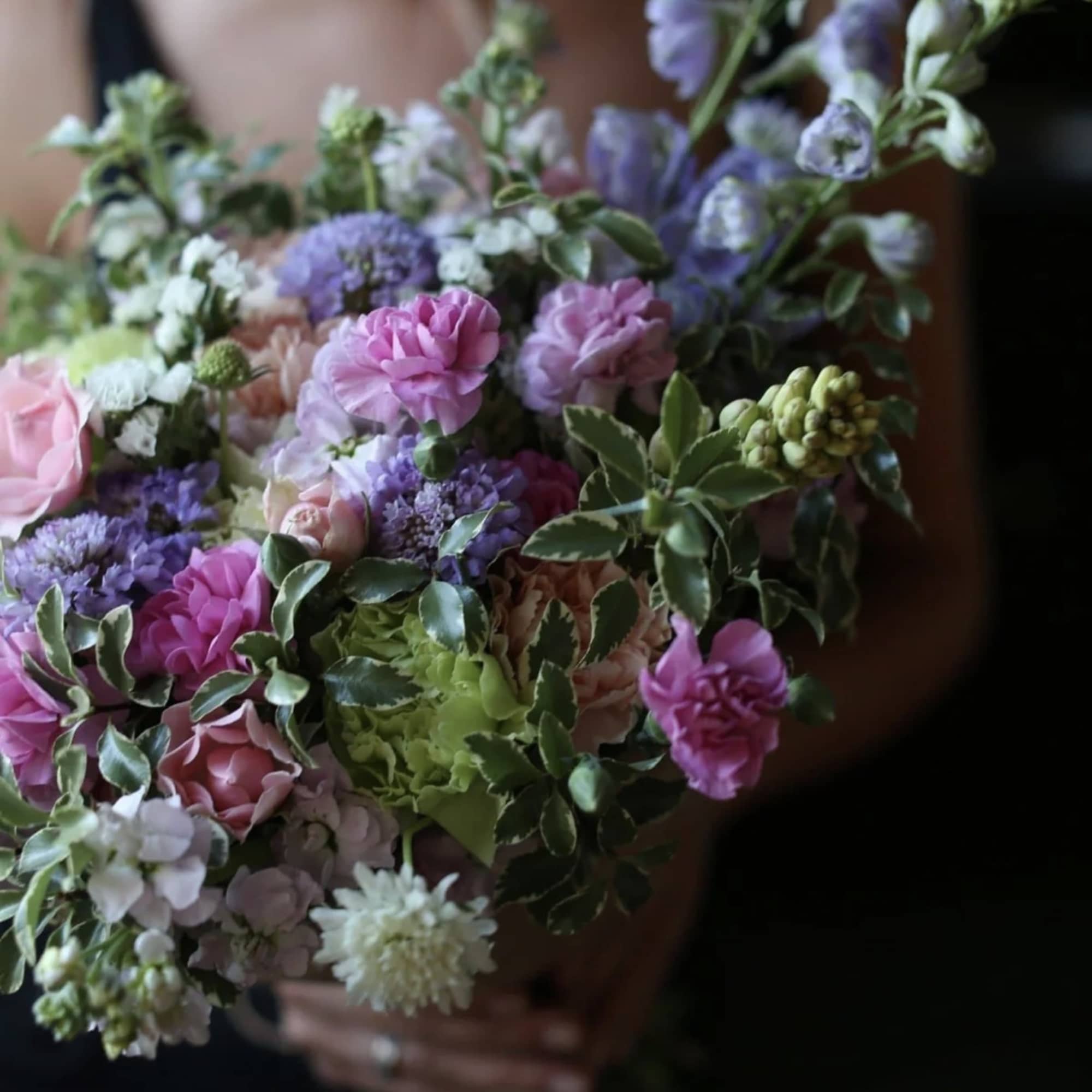 Handheld bouquet of pink, purple, and white flowers