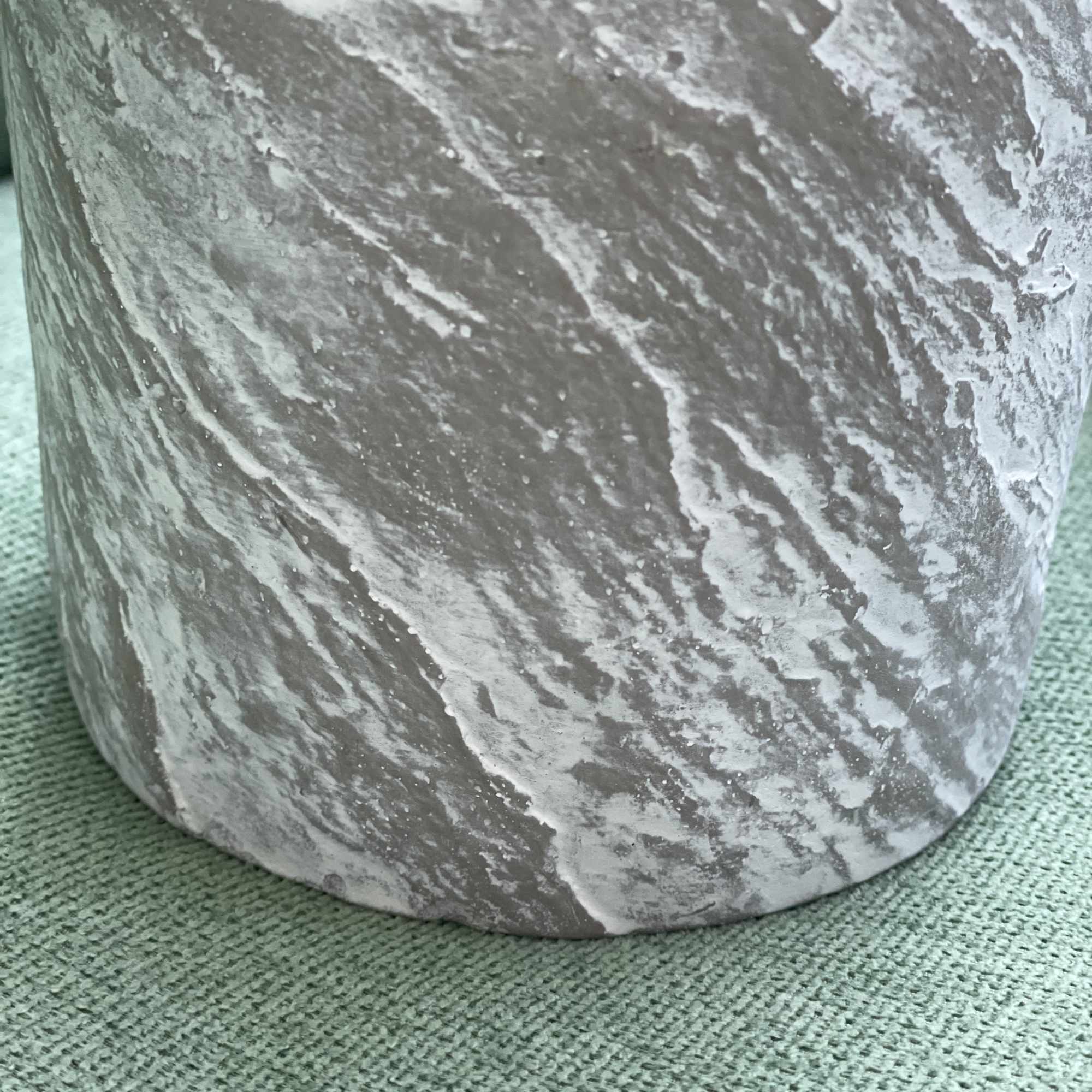 Marbled gray cylindrical vase on a green textured surface