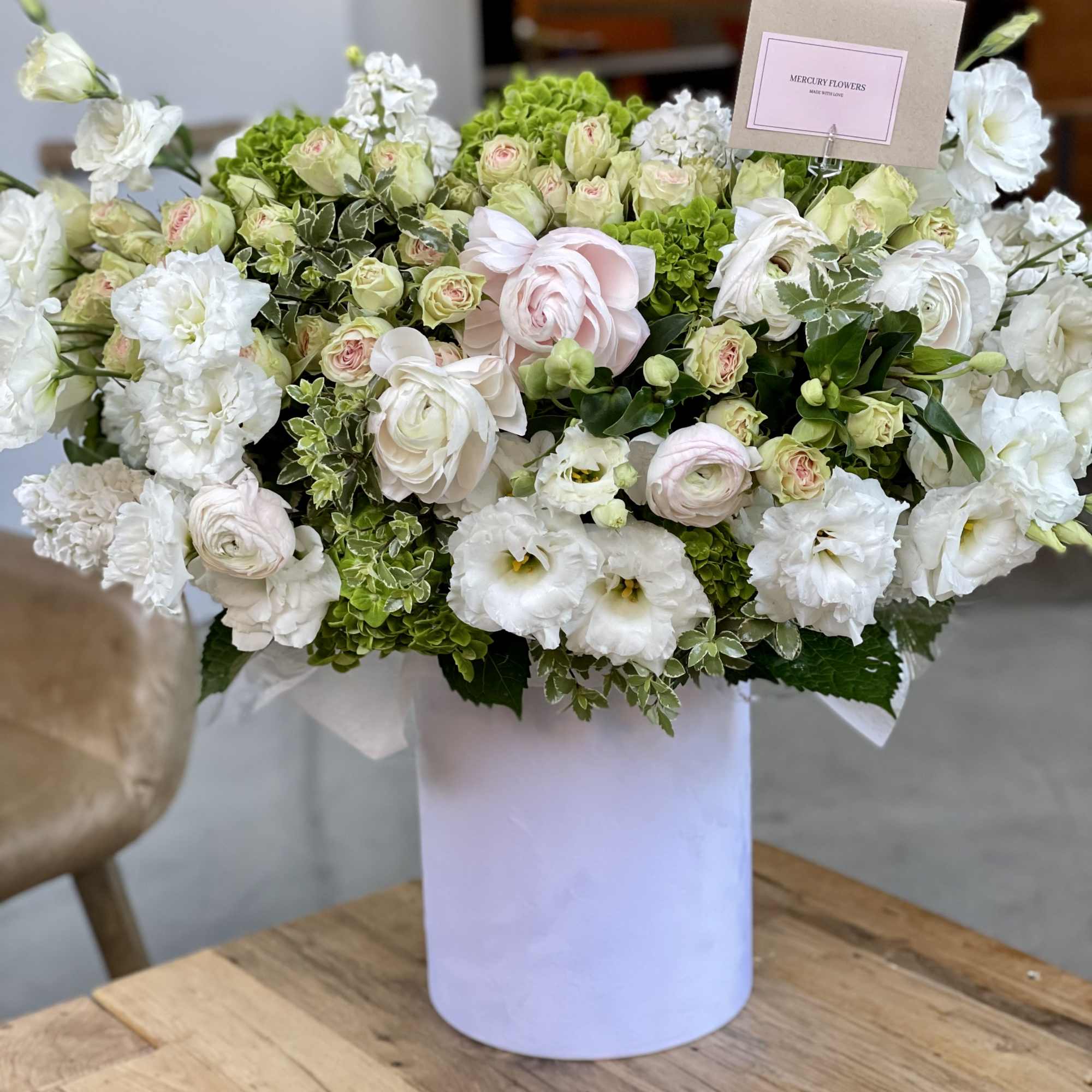 Large white and pale green floral arrangement in a white vase