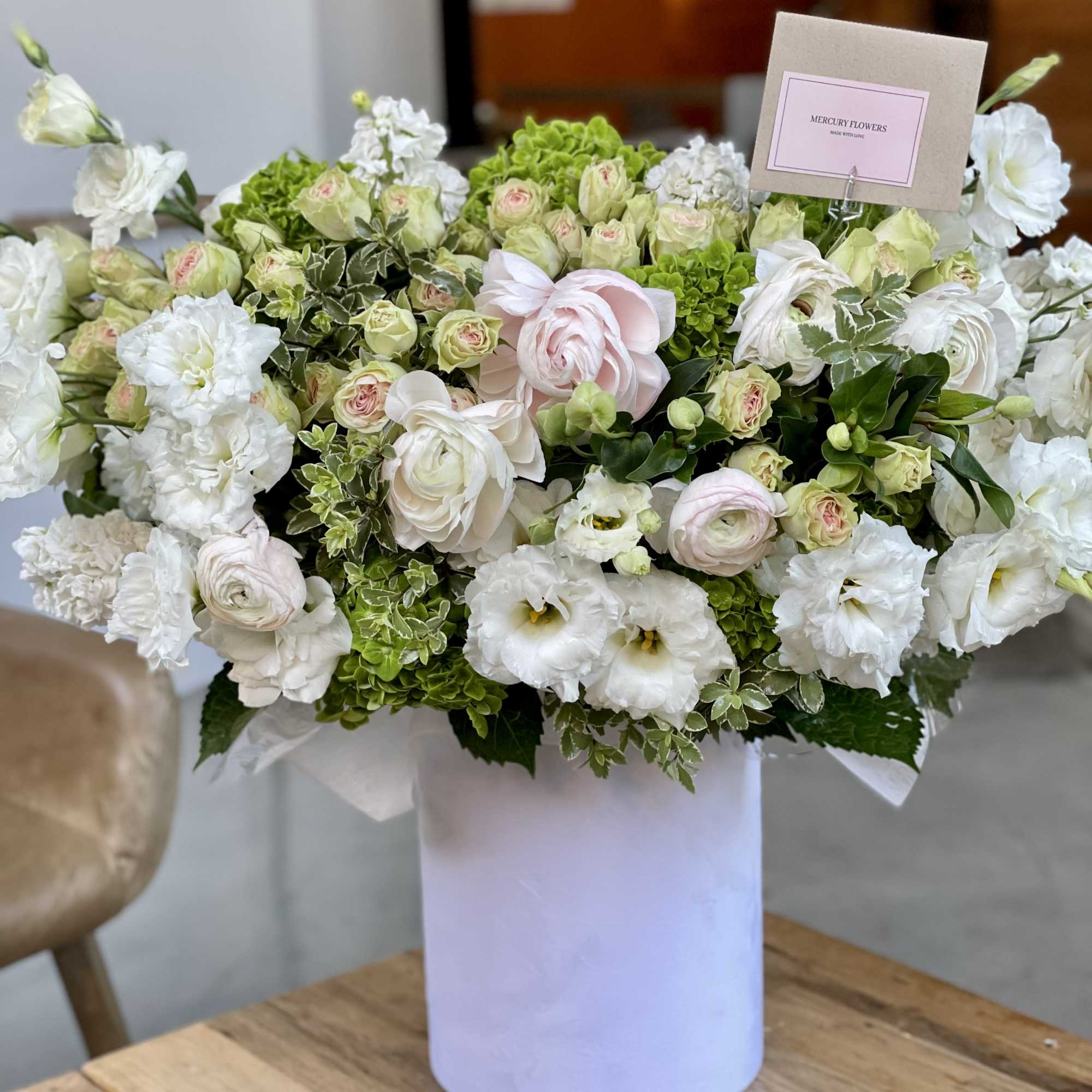 Large white and pale pink flower arrangement in a white box