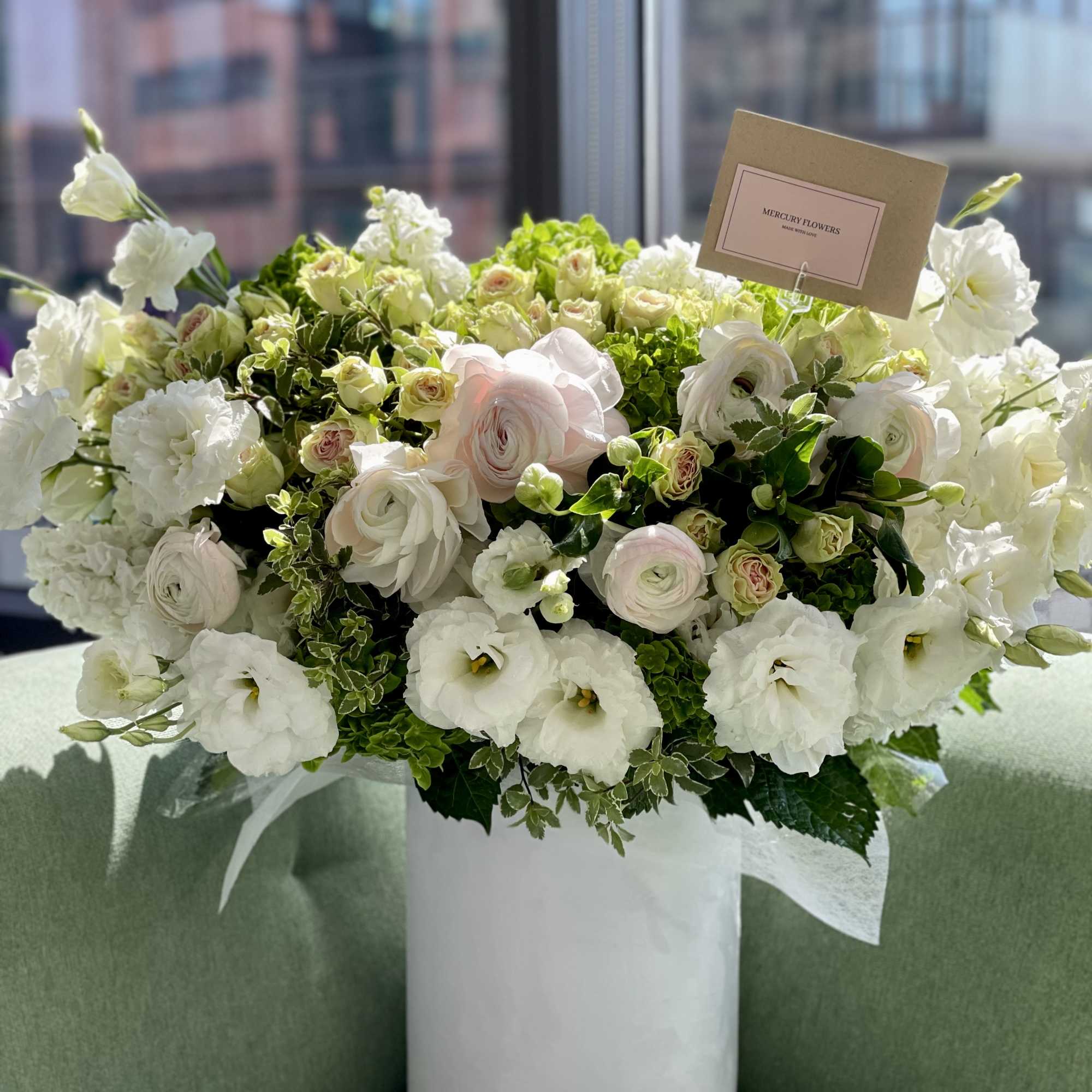 White floral arrangement in a tall white vase with a card holder