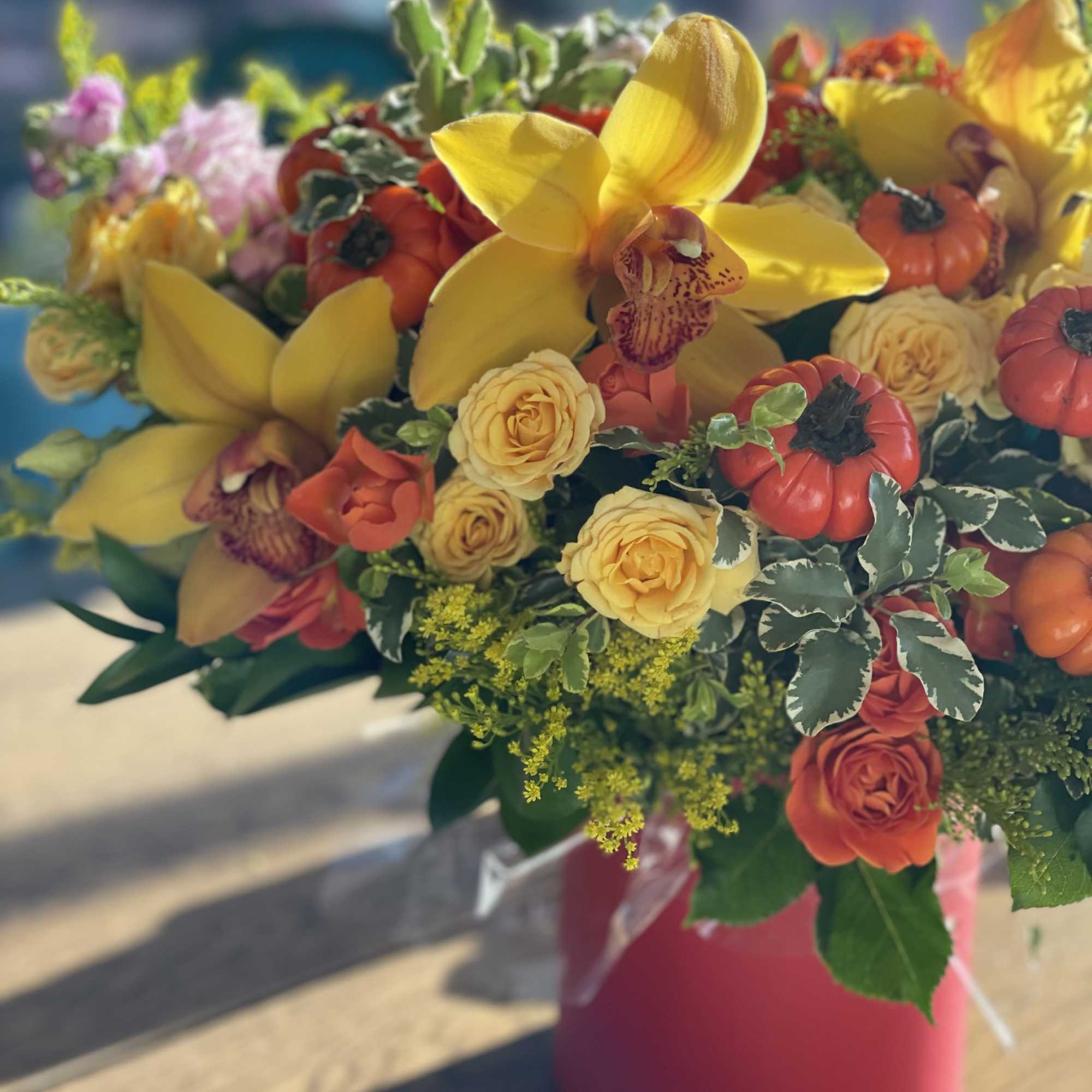 Yellow orchids and orange roses in a pink vase